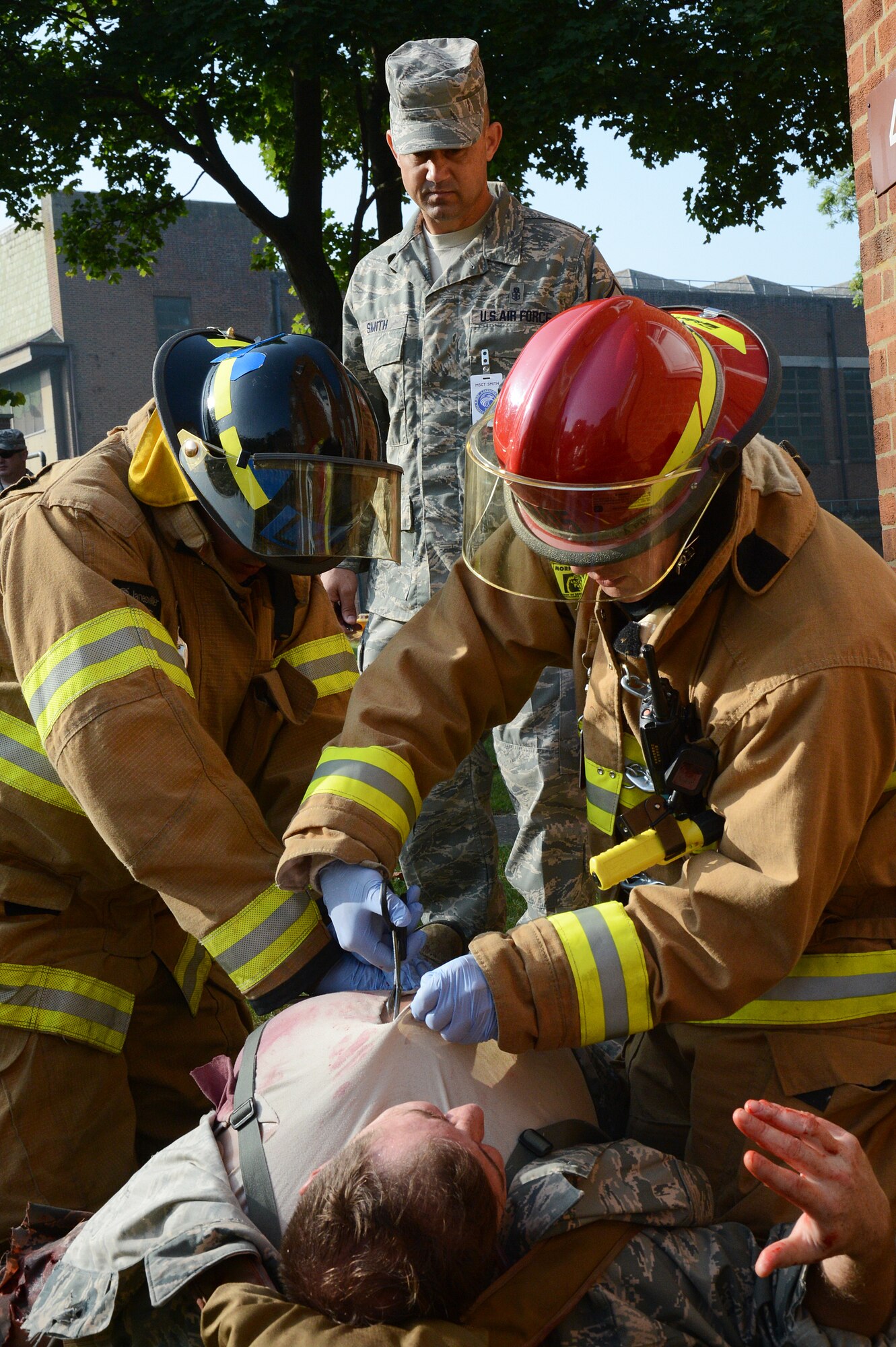 Firefighters from the 48th Civil Engineer Squadron, led by Staff Sgt. Tyler Mclain (red helmet), treat simulated patient Dave Scott, 48th Medical Group medical simulation technician, for wounds received during an active-shooter exercise while they are evaluated by Master Sgt. Darin Smith, 48th Fighter Wing Inspection Team member, on Royal Air Force Feltwell, England, Sept. 5, 2013. Responders from 48th Security Forces Squadron, 48th CES Explosives Ordnance Disposal and 48th CES Fire Department were evaluated during the training on their capabilities and proficiency. (U.S. Air Force photo by Staff Sgt. Thomas Trower/Released)