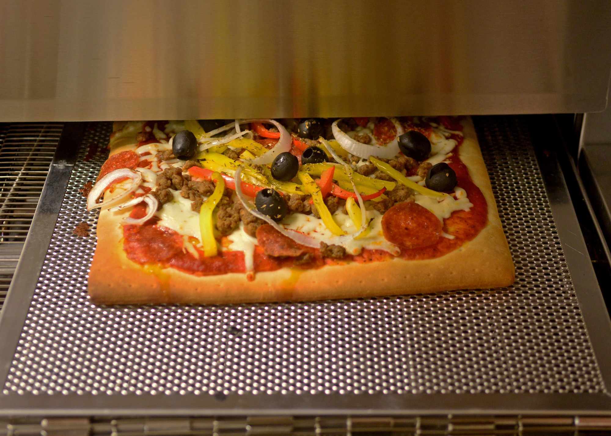 A cooked pizza comes out of a newly-installed conveyor belt oven, Sept. 9, 2013, at Aviano Air Base, Italy. The La Bella Vista club’s pizza menu currently consist of cheese, meat lovers and  margherita pizza, in small and medium sizes. (U.S. Air Force photo/Senior Airman Briana Jones)