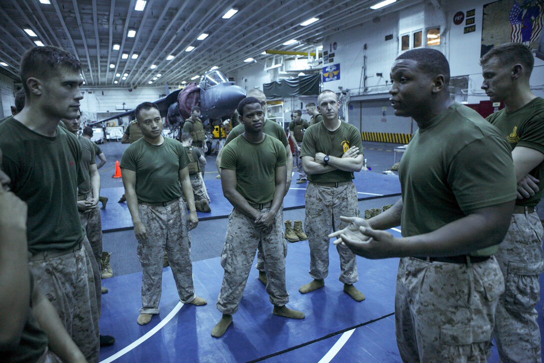 Sergeant Johnathon R. Robinson (right), a Marine Corps Martial Arts black belt instructor with Combat Logistics Battalion 31, 31st Marine Expeditionary Unit, and a native of Larned, Kan., conducts a “tie-in,” a values-based guided discussion, during Marine Corps Martial Arts training in the hanger bay here, Sept. 12. Those participating in the MCMAP training have to work around the challenges that being deployed on an amphibious warship presents, including time limitations, confined space, dim lighting and unstable fighting grounds. The 31st MEU is the Marine Corps’ force in readiness in the Asia-Pacific region and is the only continuously forward deployed MEU. 