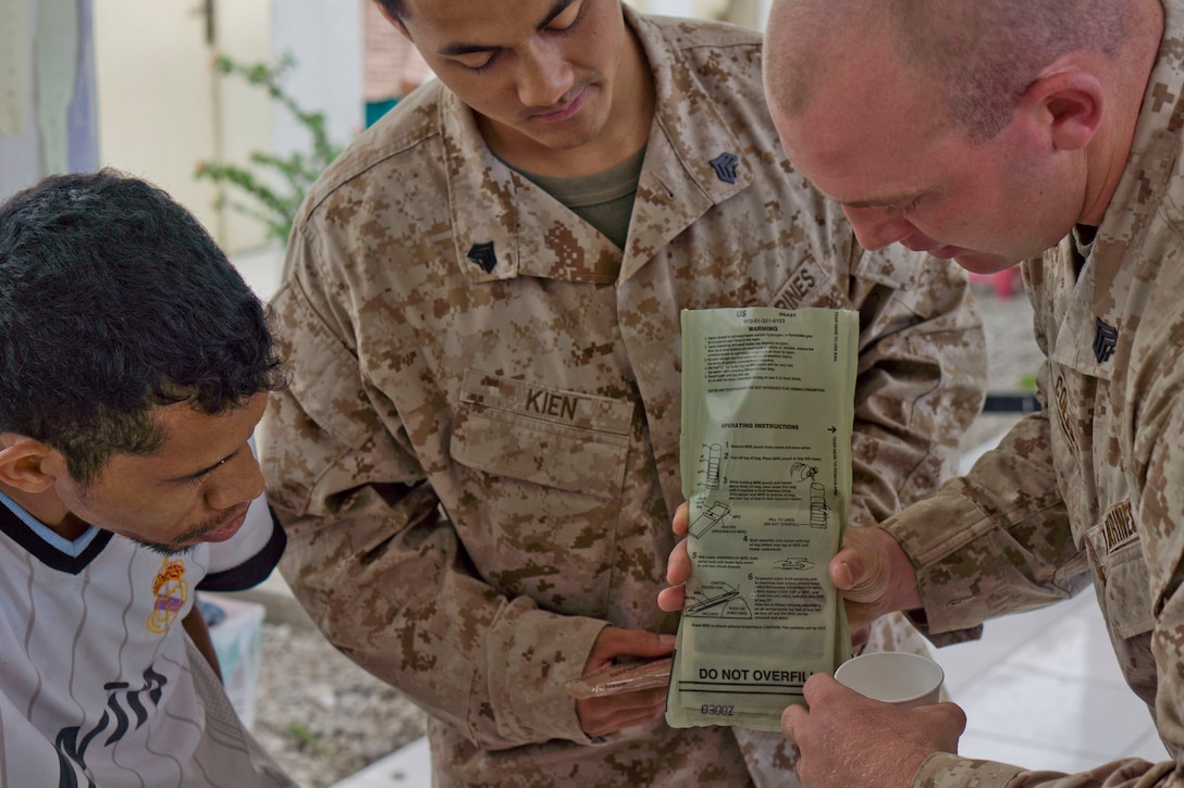 Sergeant Binh D. Kien (center), a 23-year-old field artillery cannoneer with Echo Battery, Battalion Landing Team 2nd Battalion, 4th Marines, 31st Marine Expeditionary Unit, and a native of San Jose, Calif., and Sgt. Eric D. Colley, a 25-year-old field wireman with E. Btry., BLT 2/4, 31st MEU, and a native of Middleton, Idaho, show a member of the Ahisaun Foundation for disabled persons how to use a flameless ration heater of a Meal, Ready-to-Eat during a visit here, Aug. 28. The visit was one of two events the Marines and Sailors of the 31st MEU and crew of the USS Denver (LPD 9) were able to volunteer for. The other was a visit to the Bidau Akadiru-hun elementary school. Both events were during Exercise Koolendong 13, where a battalion-sized force of the 31st MEU trained alongside Marine Rotational Force - Darwin and soldiers of the 5th Royal Australian Regiment during a week-long, live-fire exercise. The 31st MEU is the Marine Corps’ force in readiness for the Asia-Pacific region and is the only continuously forward-deployed MEU. 