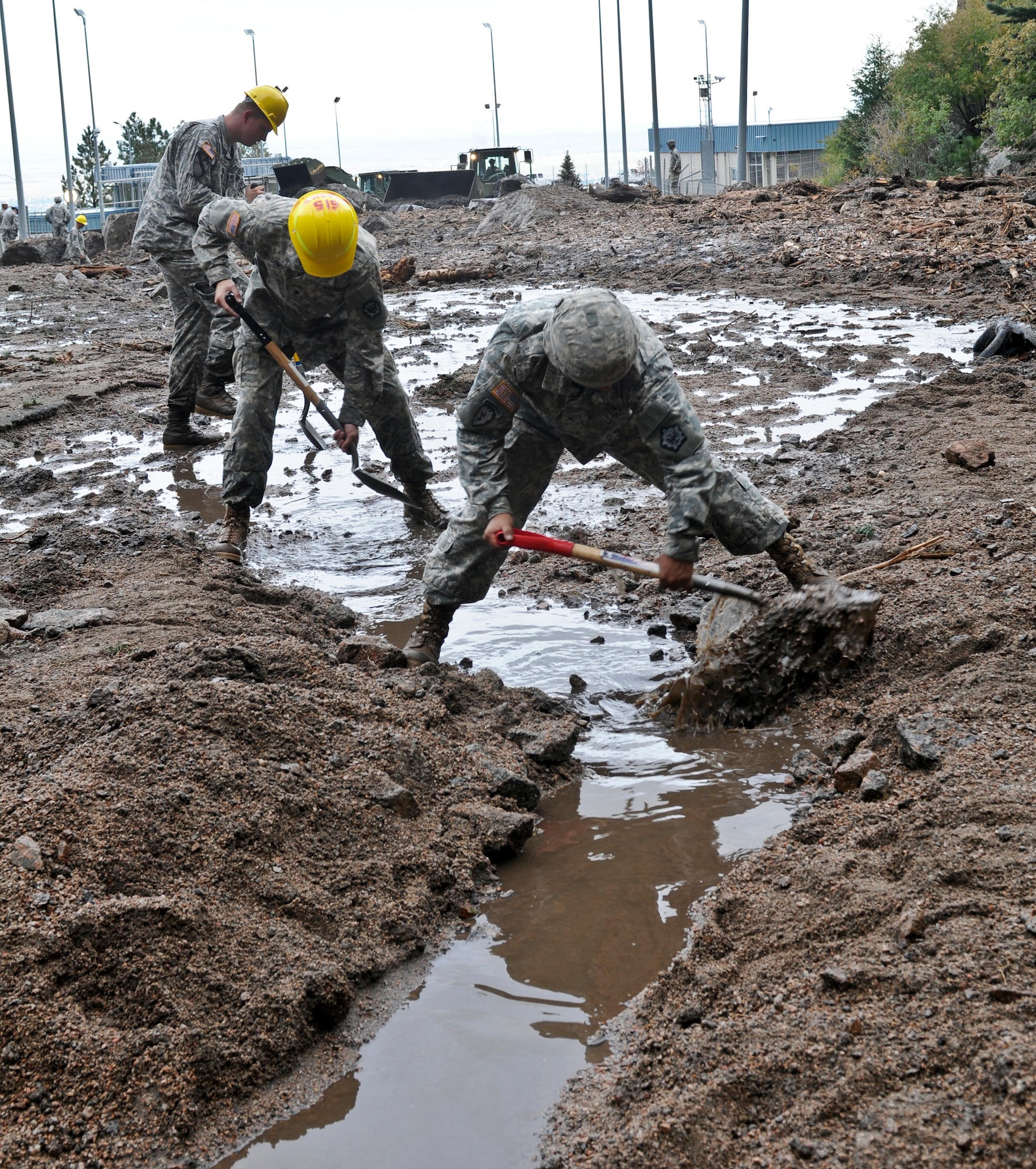 CHEYENNE MOUNTAIN AFS, Colo. -- Sgt. Robert Riojas, and Spcs. Jordan Bellows and Jason Barth, all mechanics with 615th Engineer Company, 52nd Engineer Battalion, dig a drainage ditch to remove water from a work area at the Cheyenne Mountain Air Force Station, Sept. 13, 2013. The 615th Eng. is part of the severe weather reaction team and responded to a catastrophic mudslide on the AFS. (U.S. Army photo/Sgt. William Smith)

