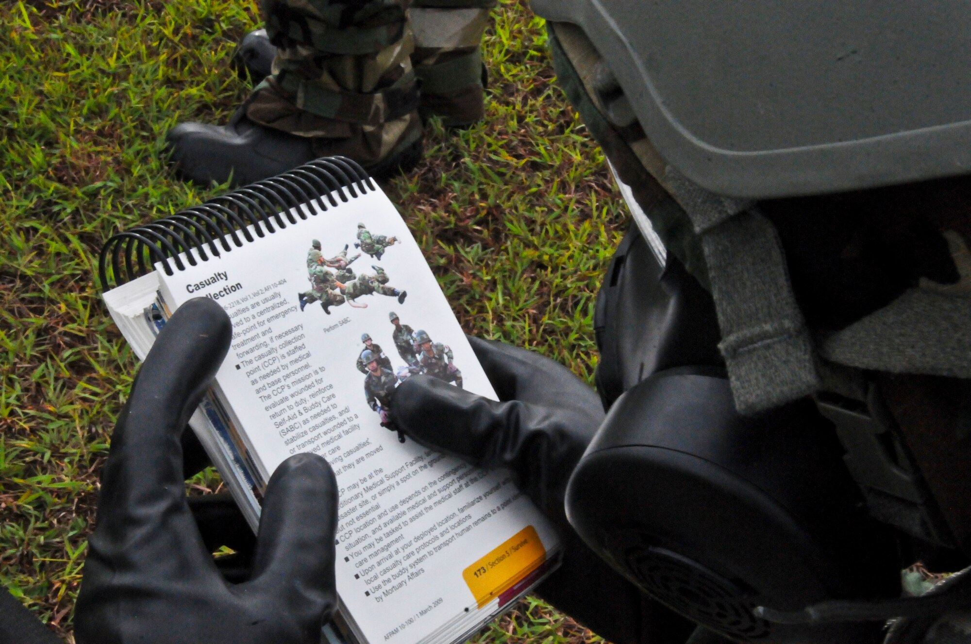 An Airman reviews the Airman’s Manual during a self-aid buddy care simulation at the Ability to Survive and Operate Rodeo Sept. 13, 2013, on Andersen Air Force Base, Guam. Airmen demonstrated their ability to perform in heightened awareness situations during the rodeo. (U.S. Air Force photo by Airman 1st Class Amanda Morris/Released)