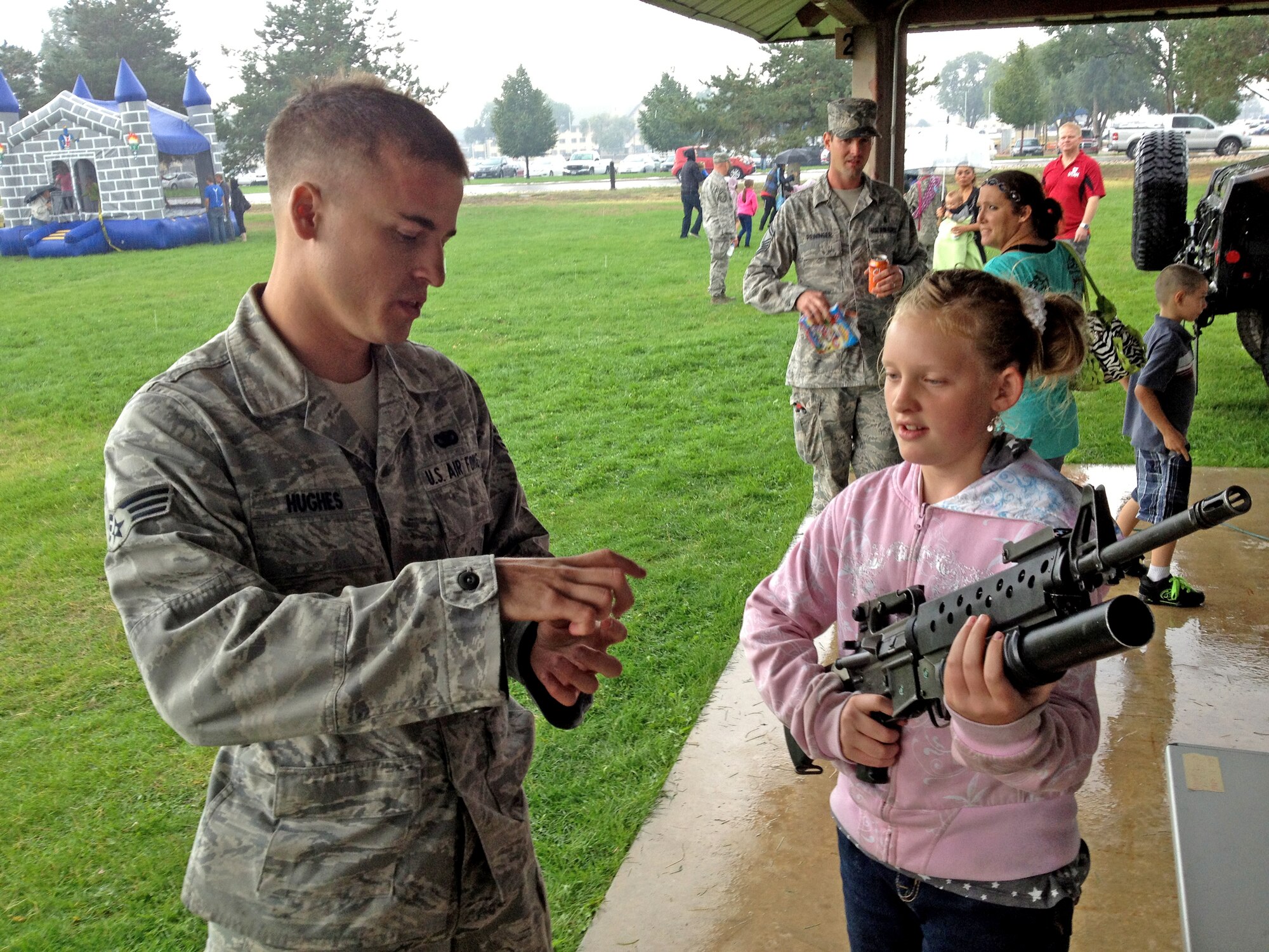Senior Airman Jared Hughes, 419th Security Forces Squadron, explains a military rifle to McKenna, one of hundreds of family members who showed up to the wing’s Family Day today. (Courtesy photo)