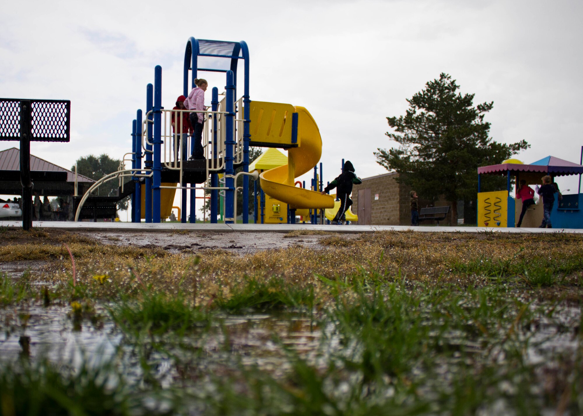 Undeterred by rain, a family plays on the playground at the base’s Centennial Park during the 419th Fighter Wing’s Family Day today. (U.S. Air Force photo/Tech. Sgt. Richard Gonzales)
