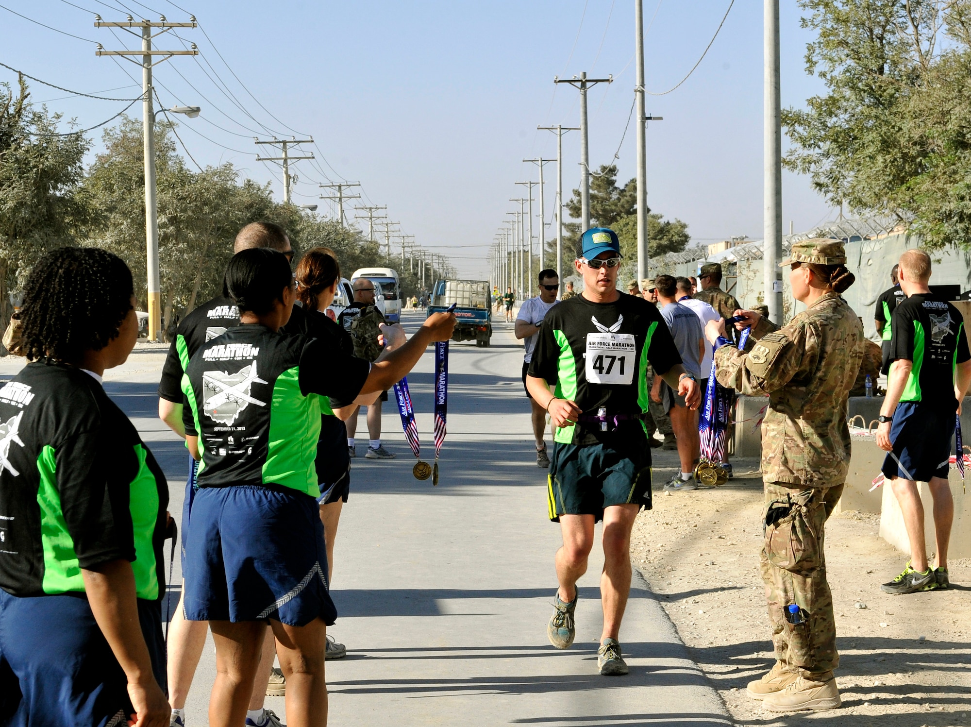 Volunteers award runners finishers medals at the finish line during the 3rd annual Bagram Marathon here Sept. 15, 2013. More than 700 people participated in either the full-marathon or the half-marathon. The Bagram Marathon is an extension of the Air Force Marathon held at Wright Patterson Air Force Base, Dayton, Ohio, Sept. 21. (U.S. Air Force photo/Staff Sgt. Stephenie Wade)