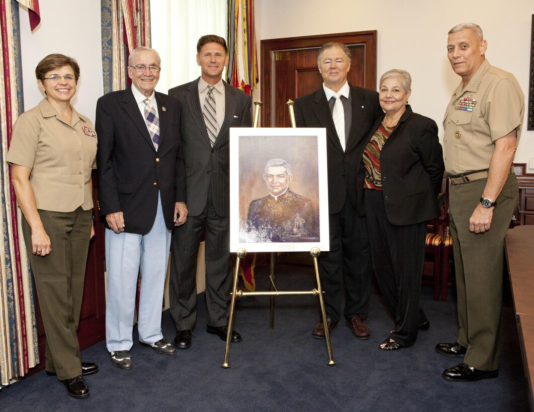 From left, Chaplain of the Marine Corps, Rear Admiral Margaret Kibben, U.S. Navy Ret. Capt. Ted Bronson, Assistant Secretary of the Navy, Juan M. Garcia, III, Mike "Chip" Lofton, Sharon Lofton, and the Assisant Commandant of the Marine Corps, Gen. John M. Paxton, Jr. pose for a photo around the portrait of Father Vincent Capodanno at the Pentagon in Arlington, VA, on Aug. 30, 2013. (U.S. Marine Corps photo by Cpl. Tia Dufour/Released)