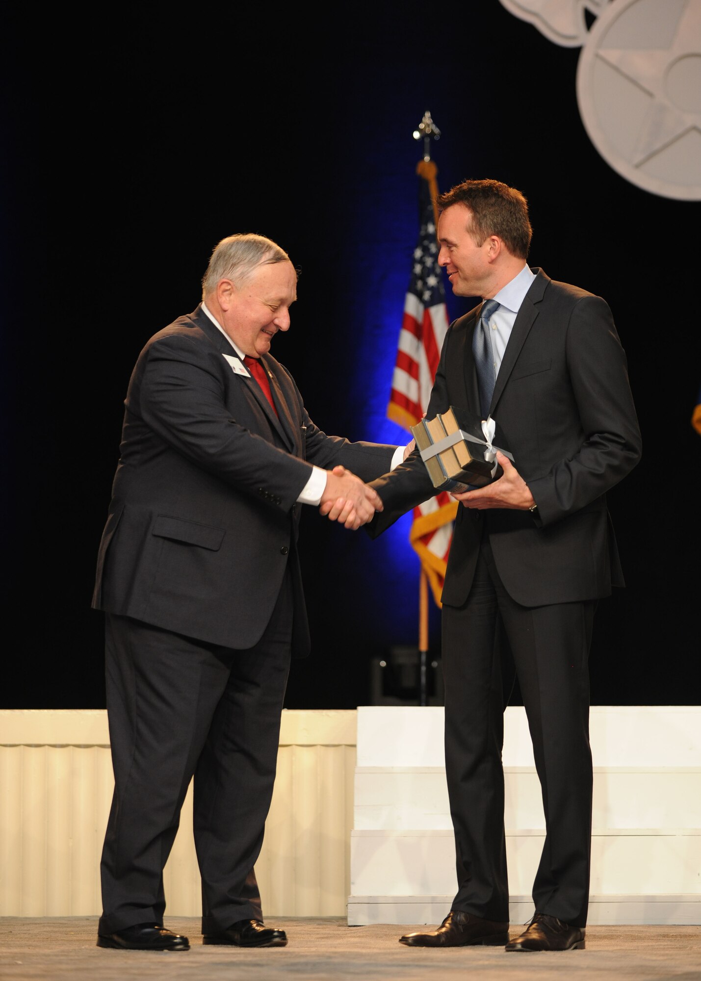 George K. Muellner presents Acting Secretary of the Air Force Eric Fanning books written by Air Force innovators of the past at the Air Force Association’s 2013 Air & Space Conference and Technology Exposition Sept. 16, 2013, in Washington, D.C. Muellner is the Chairman of the Board for the Air Force Association. (U.S. Air Force photo/Airman 1st Class Aaron Stout)