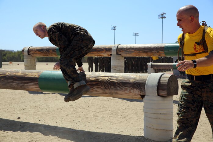 A recruit of Company E, 2nd Recruit Training Battalion, hurdles over a wood beam during the Obstacle Course aboard Marine Corps Recruit Depot San Diego, Sept. 5. Recruits must perform the course while wearing combat utilities and boots.