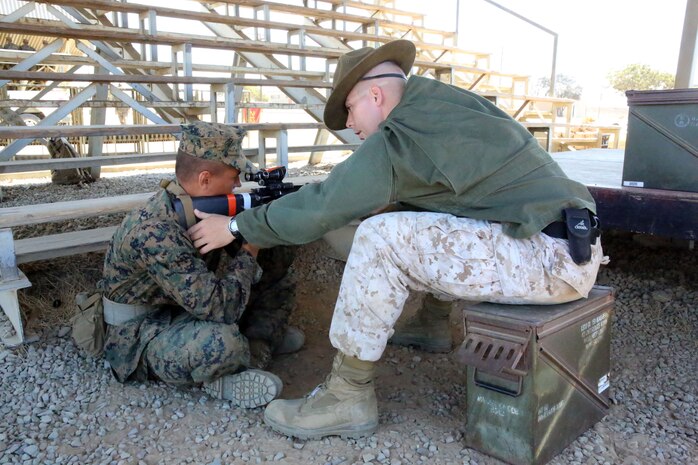 Recruit Zachery J. Gibson of Platoon 2121, Company F, 2nd Recruit Training Battalion, aims in the sitting position while Sgt. Michael L. Steele, Combat Marksmanship Trainer chief instructor, corrects his position at Edson Range aboard Marine Corps Base Camp Pendleton, Calif., Sept. 4.