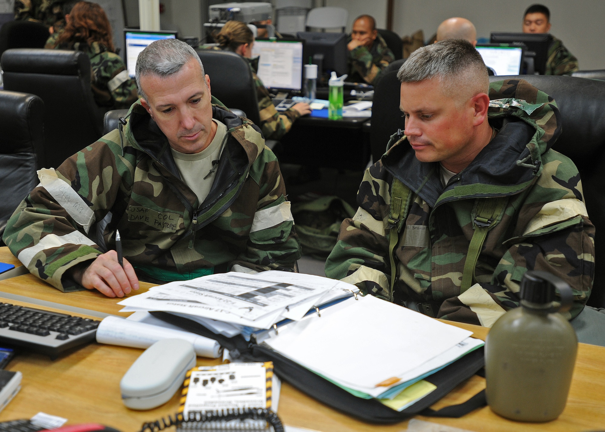 Col. David Pastore, 15th Maintenance Group commander, left, and Maj. Jessie Bogart, Hawaii Air National Guard 154th Maintenance Group deputy, right, review exercise procedures during an Operational Readiness Exercise at the Wing Operations Center at Joint Base Pearl Harbor-Hickam, Hawaii, Sept. 12, 2013. Readiness exercises focus on testing the ability of Airmen to don mission-oriented protective posture, or “MOPP” gear, and survive simulated chemical attacks in an austere environment while still proceeding with the mission. (U.S. Air Force photo/Tech. Sgt. Jerome S. Tayborn)