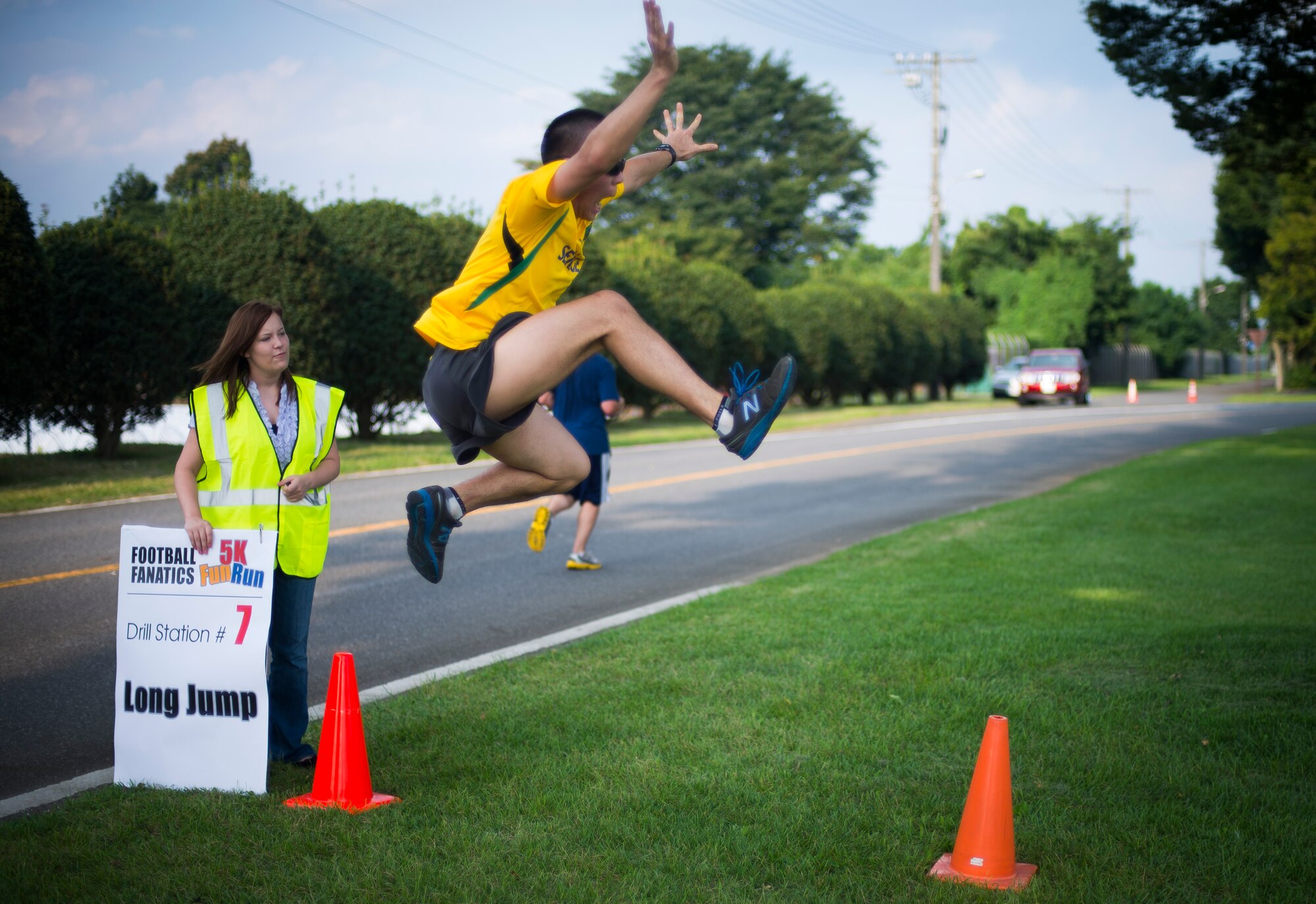A volunteer performs the long jump during the Combined Federal Campaign 5K Fun Run Sept. 13, 2013 at Yokota Air Base, Japan. There were a total of seven obstacles to include the 40-meter dash and hurdles. (U.S. Air Force photo by Staff Sgt. Chad C. Strohmeyer/released)