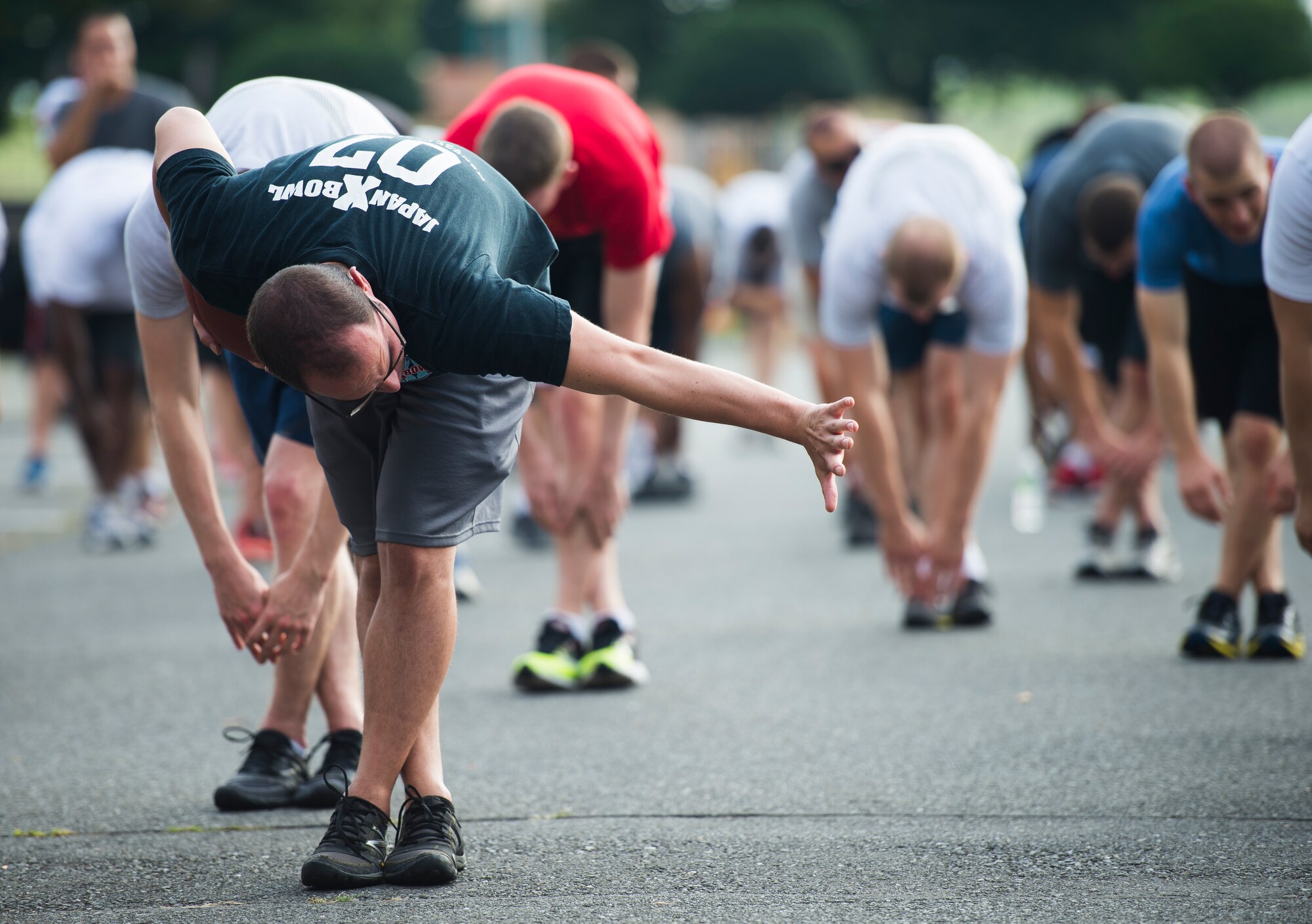 A participant does the “Heisman” while stretching prior to the start of the Combined Federal Campaign 5K Fun Run Sept. 13, 2013 at Yokota Air Base, Japan. The volunteers were encouraged to wear their favorite football jersey while running. (U.S. Air Force photo by Staff Sgt. Chad C. Strohmeyer/released)