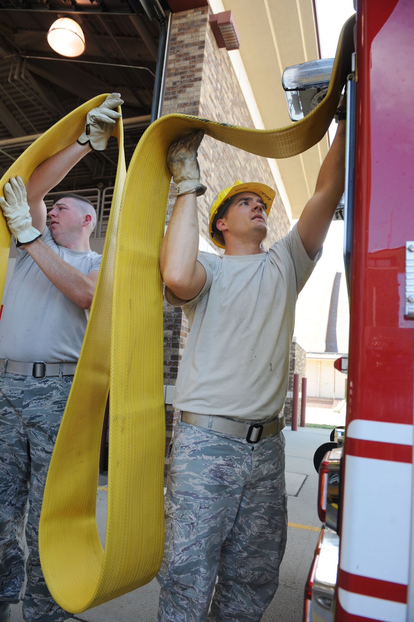 Airman 1st Class Levi Hickey(left), 28th Civil Engineer Squadron firefighter, and Senior Airman Zechariah Engwall, 28th CES vehicle operator, reload a hose onto a fire truck after testing equipment outside the fire station at Ellsworth Air Force Base, S.D., Sept. 11, 2013. Engwall has been awarded the title of 2012 Department of Defense Firefighter of the Year for his superior job performance and outstanding contribution to the fire service throughout the year. (U.S. Air Force photo by Airman 1st Class Rebecca Imwalle/Released)