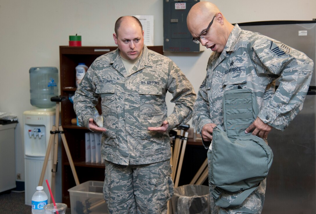 Staff Sgt. Theodore Van De Sample, 47th Civil Engineer Squadron readiness and emergency flight NCO in charge, instructs Master Sgt. Carl James, 47th Medical Group and 47th Flying Training Wing Wing Staff Agencies first sergeant, on where to holster his gas mask carrier during a chemical, biological, radiological and nuclear training course at Laughlin Air Force Base, Texas, Sept. 12, 2013. James was trained on all of his issued chemical protective gear to ensure he was properly educated before deploying. (U.S. Air Force photo/Senior Airman John D. Partlow)