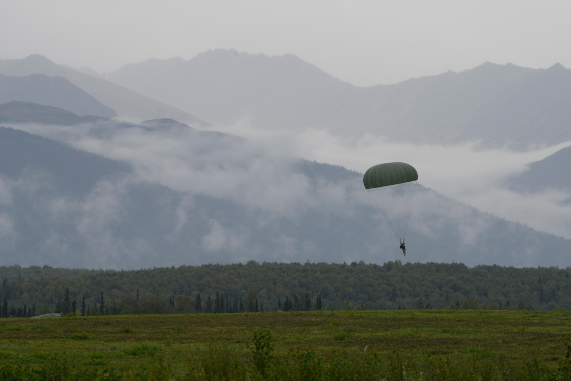 JOINT BASE ELMENDORF-RICHARDSON, Alaska -- A Soldier from the 6th Engineer Brigade in front of the clouded mountains of the Malamut drop zone after jumping from a Marine Corps C130J Sept. 6th. Marine Aerial Refueler Transport Squadron 152 (VMGR-152) flew 14 hours on three C-130Js, more than 7,400 miles, from tropical Okinawa to sub-arctic Alaska for two weeks to train at unique ranges and build their core mission skills on tactical navigation, aerial delivery and threat reaction. (U.S. Air Force Photo/Airman 1st Class Omari Bernard)