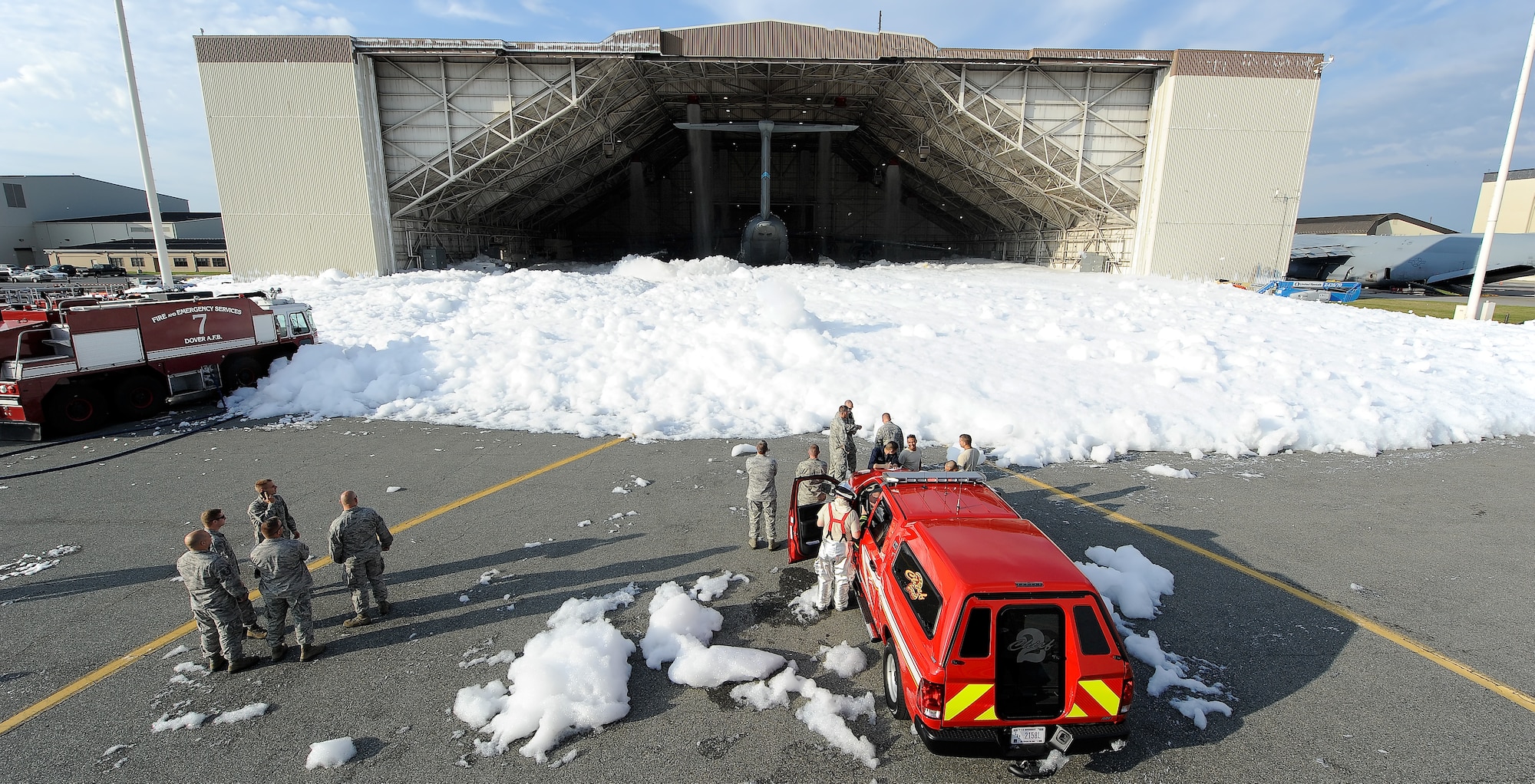 Personnel from the 436th Civil Engineer Squadron, Fire Department, respond to the inadvertent release of fire suppression foam in hangar 706 on Sept. 16, 2013 at Dover Air Force Base, Del. The firefighters worked to dissipate the foam using water sprayed from a ladder truck. (U.S. Air Force photo/Greg L. Davis)