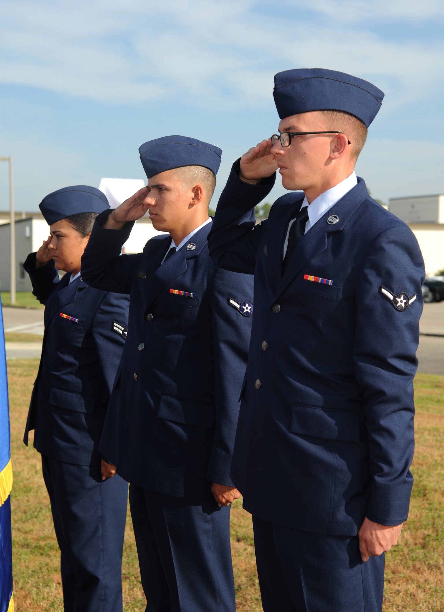 Airman 1st Class Janice Dones-Crispin and Airmen Evan Ryan and Charles Keyser, 338th Training Squadron, render a salute during the singing of the National Anthem at the street dedication ceremony honoring a former technical training student, Chief Master Sgt. Richard Etchberger, Sept. 16, 2013, Keesler Air Force Base, Miss. Etchberger’s son, Cory Etchberger, assisted with the unveiling of a street sign and a memorial stone at the event.  (U.S. Air Force photo by Kemberly Groue)