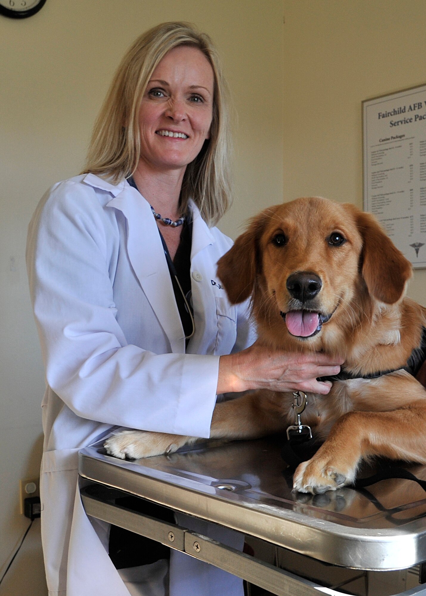 Julie Sowa, base veterinarian, poses with Stella, a golden retriever, at the Fairchild Air Force Base veterinarian clinic, Sept. 12, 2013. Sowa is new to Team Fairchild and also works part time in Yakima, Wash. at an emergency vet clinic. (U.S. Air Force photo by Senior Airman Mary O'Dell/Released)