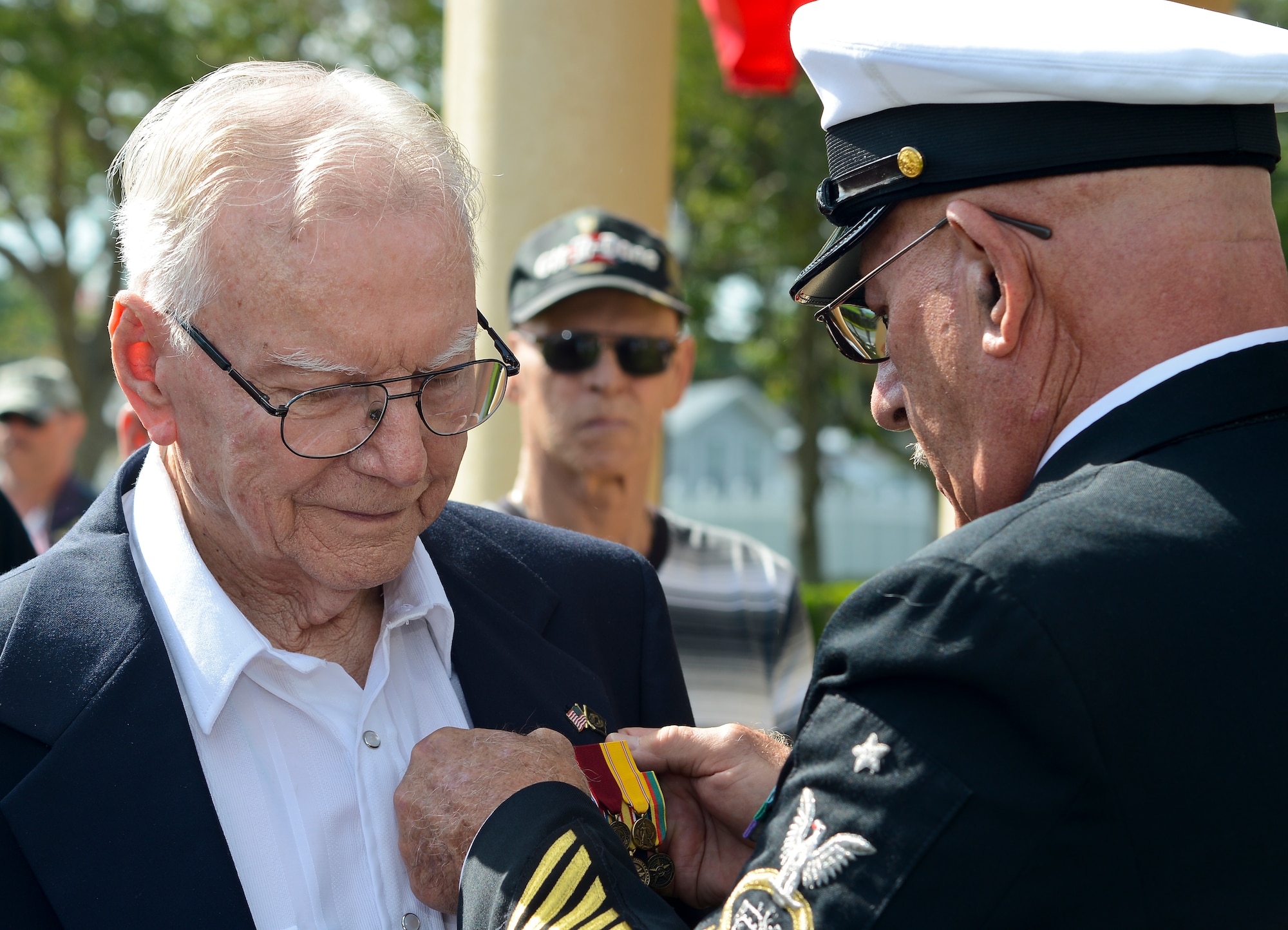 Retired Senior Chief Petty Officer Paul J. Rizzo pins on Petty Officer 2nd Class McPherson Plecker, a World War II veteran and prisoner-of-war, nine military decorations during a tribute honoring Plecker at The Palms of Largo in Largo, Fla., on Sept. 14, 2013. During WWII, Plecker defended Wake Island and endured four  years as a POW in Japanese and Chinese war camps. (U.S. Air Force photo by Senior Airman Shandresha Mitchell/Released)
