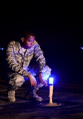 Airman 1st Class Issac Butler, 6th Operations Squadron airfield management operations coordinator, inspects a taxiway edge light on the flightline, Sept 5, 2013 at MacDill Air Force Base, Fla.  Airfield management is responsible for ensuring that 11 taxiways and one runway are fully operational twenty-four hours a day. (U.S. Air Force photo by Senior Airman Melanie Bulow-Kelly/Released)