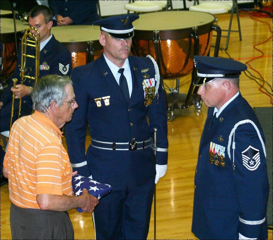 TSGT Brian Erickson and MSGT Steve Burdick present a folded American flag to Jack Lay, a Korean War fighter pilot, after the moving flag folding ceremony done during a concert in Oneida, TN on June 23, 2013