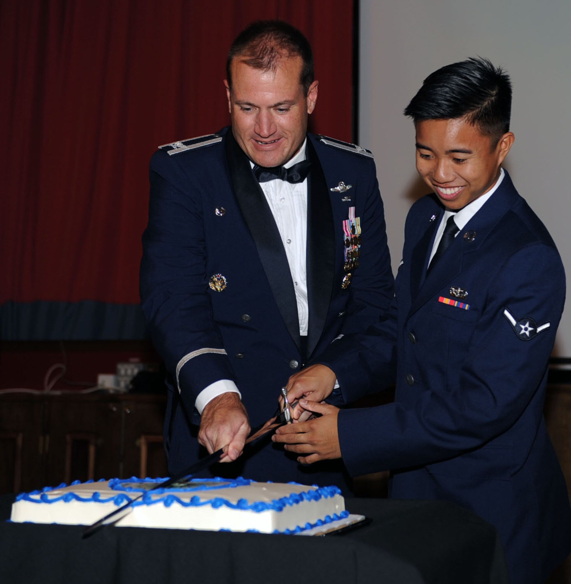 U.S. Air Force Col. Kenneth T. Bibb Jr., 100th Air Refueling Wing commander, center, and Airman Jose Belizario, 100th Force Support Squadron fitness specialist, right, cut the cake using a saber Sept. 14, 2013, during the Air Force Ball on RAF Mildenhall, England.  The event celebrated the Air Force's 66 years as an independent service. (U.S. Air Force photo by Airman 1st Class Preston Webb/Released)