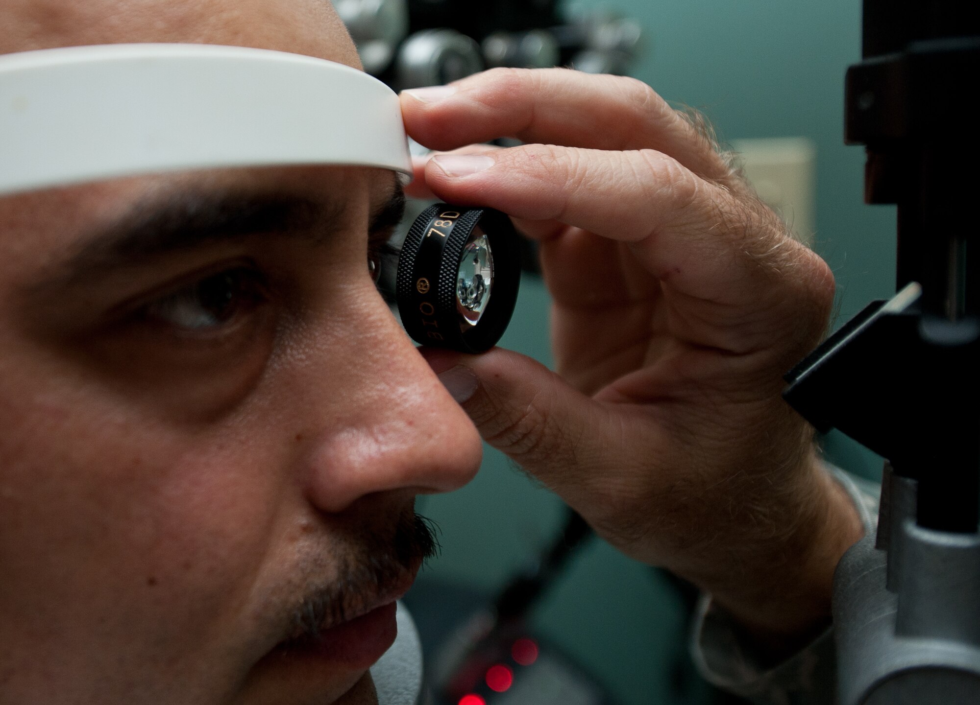 Maj. Bryan Kemper, 28th Medical Operations Squadron optometrist, uses a lens to magnify and view the eye of Master Sgt. Juan Lopez, 28th Aircraft Maintenance Squadron production superintendent during an eye exam at Ellsworth Air Force Base, S.D., Sept. 12, 2013. By using magnification, Kemper was able to evaluate the retna and back of the eye to ensure the entire organ was healthy. (U.S. Air Force photo by Airman 1st Class Alystria Maurer/Released)