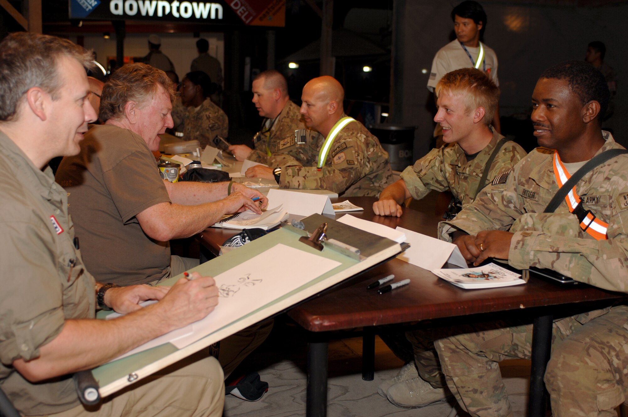 Cartoonists from the National Cartoonists Society draw different Coalition force members as part of a USO tour at the Kandahar Boardwalk at Kandahar Airfield, Afghanistan, Sept. 7, 2013. The boardwalk has hosted countless USO, morale and band tours, to include performances from country singers Toby Keith and Billy Ray Cyrus during the seven-year span the boardwalk has been in its current location. (U.S. Air Force photo/Senior Airman Jack Sanders)