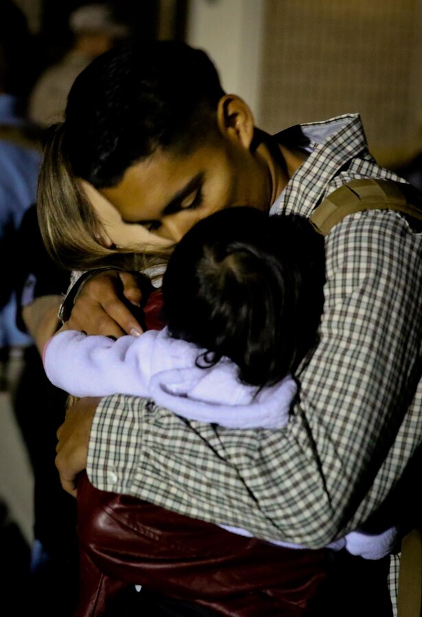 Lance Cpl. Ernesto Menjivar, rifleman, Bravo Company, 1st Battalion, 1st Marine Regiment, and a native of Los Angeles, hugs his wife, Ashley, and daughter, Lucy, before leaving on a deployment at the Camp Horno parade deck here, Sept. 14, 2014. Marines with the company will provide site security at an embassy in the Middle East. The servicemembers focused on nonlethal training for scenarios similar to rioting civilians prior to their deployment.