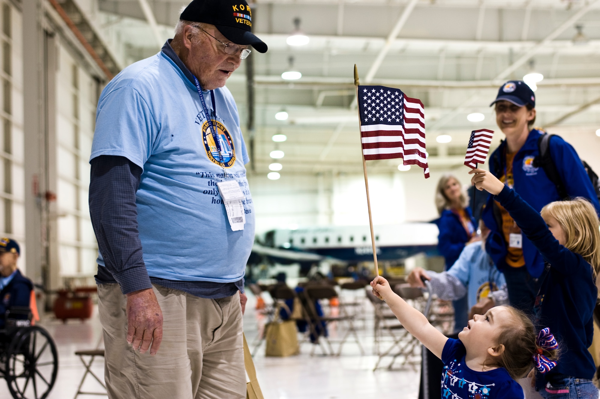 A child presents a U.S. flag to a Korean War veteran Sept. 16, 2013, at the Denver International Airport. The 124 veterans were returning from a trip to Washington where they saw the monuments constructed in their honor. Honor Flight Northern Colorado offers free trips to the district for World War II and Korean War veterans, as well as Purple Heart recipients from any war. (U.S. Air Force photo by Airman 1st Class Riley Johnson/Released)