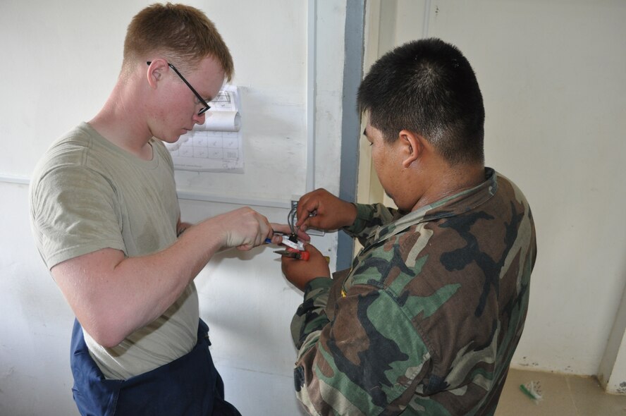U.S. Air Force Senior Airman Timothy Janca, electrician from the 18th Civil Engineer Squadron, Kadena Air Base, Japan, installs a light switch with electrician Sgt 2nd Class Sat Sovannarith, Royal Cambodian Armed Forces  at a health center Sept. 11, 2013, during Operation Pacific Angel 13-5 at Takeo Province, Cambodia. The health center is one of three undergoing renovations. Thirty-six U.S. forces and RCAF have teamed up to complete renovations scheduled to end September 14. (U.S. Air Force photo/Senior Master Sgt. Allison Day)
