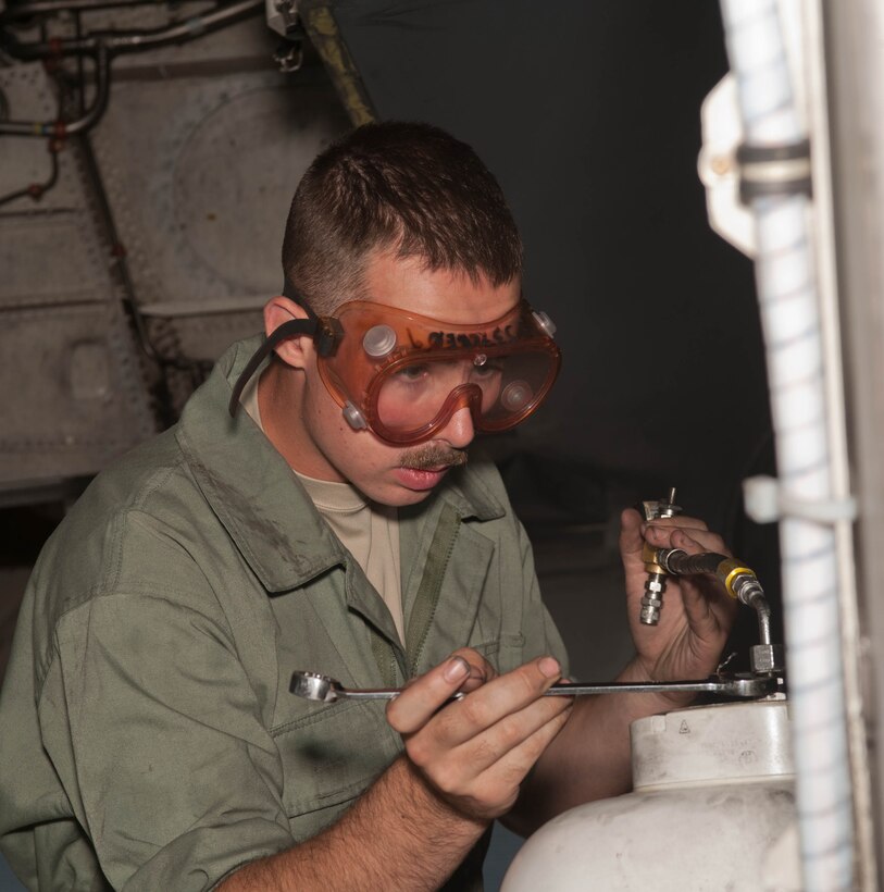 Airman 1st Class William Becker, 28th Aircraft Maintenance Squadron B-1 bomber crew chief, services the main gear strut on a B-1 during a routine inspection at Ellsworth Air Force Base, S.D., Sept. 10, 2013. Prior to flight, crew chiefs will inspect and perform various functional checks on the B-1 to ensure it has been properly serviced with fuel, hydraulic fluid and liquid oxygen. (U.S. Air Force photo by Airman 1st Class Zachary Hada/Released)