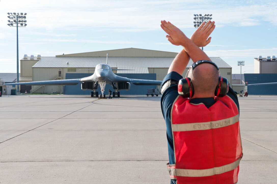 Senior Airman Neal Larson, 28th Aircraft Maintenance Squadron B-1 bomber crew chief, marshals a B-1 on the flightline prior to takeoff at Ellsworth Air Force Base, S.D., Sept. 10, 2013. In addition to other maintenance tasks, crew chiefs perform inspections, launch, recover and refuel aircraft. (U.S. Air Force photo by Airman 1st Class Zachary Hada/Released)