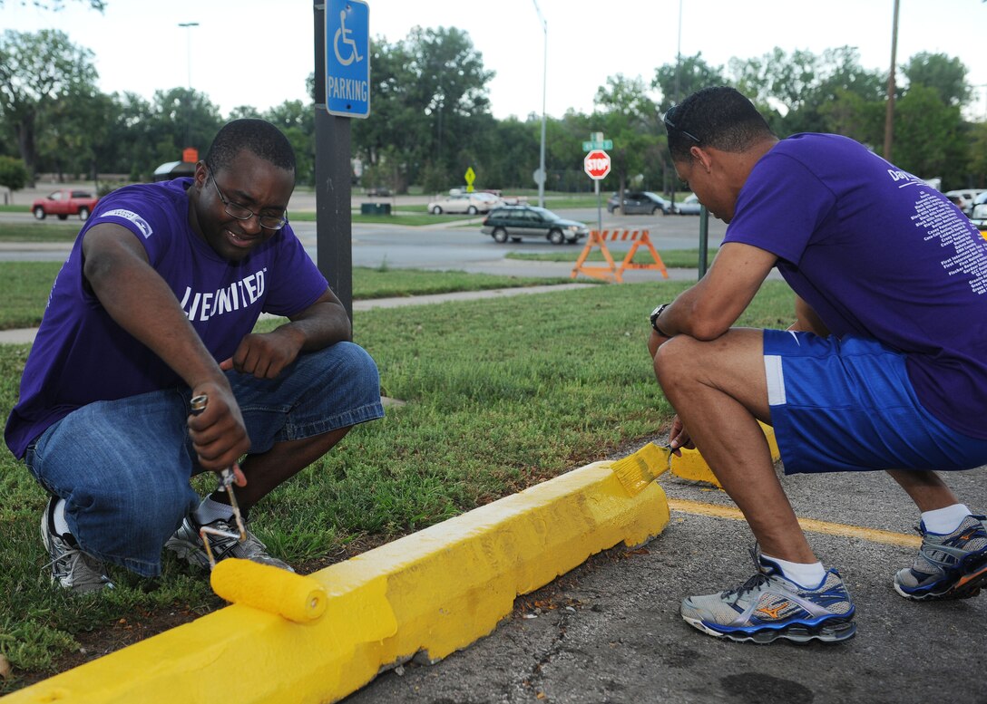 Staff Sgt. Kevin Spears, 28th Medical Support Squadron medical affirmative claim support technician (left) and Master Sgt. Correy Hodge, 28th MDSS NCO in charge of medical materiel, paint parking blocks during the United Way of the Black Hills Day of Caring in Rapid City, S.D., Sept. 5, 2013. Once a year, volunteers from across the Black Hills unite to complete community projects in an effort to help those struggling economically. (U.S. Air Force photo by Airman 1st Class Rebecca Imwalle/Released)