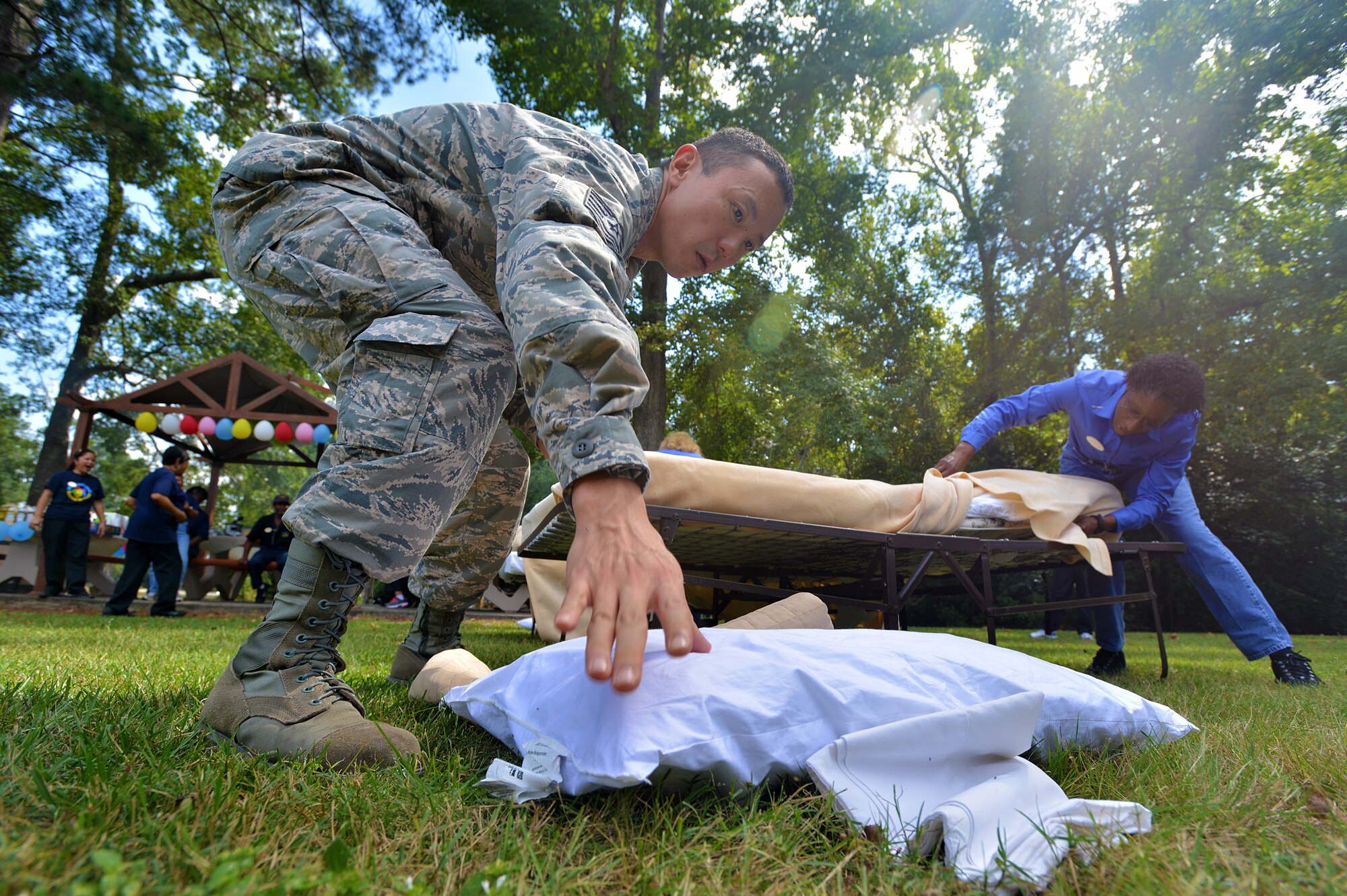 Tech. Sgt. Kent Kaisaki, Carolina Pines Inn assistant lodging manager, reaches for a pillow during a bed making competition held as part of international housekeeping week, Shaw Air Force Base, S.C., Sept. 13, 2013. International housekeeping week is an Air Force-wide event, held on many bases to show appreciation for the hard work that housekeepers do and give them a chance to relax and have fun. (U.S. Air Force photo by Airman 1st Class Jensen Stidham/Released)