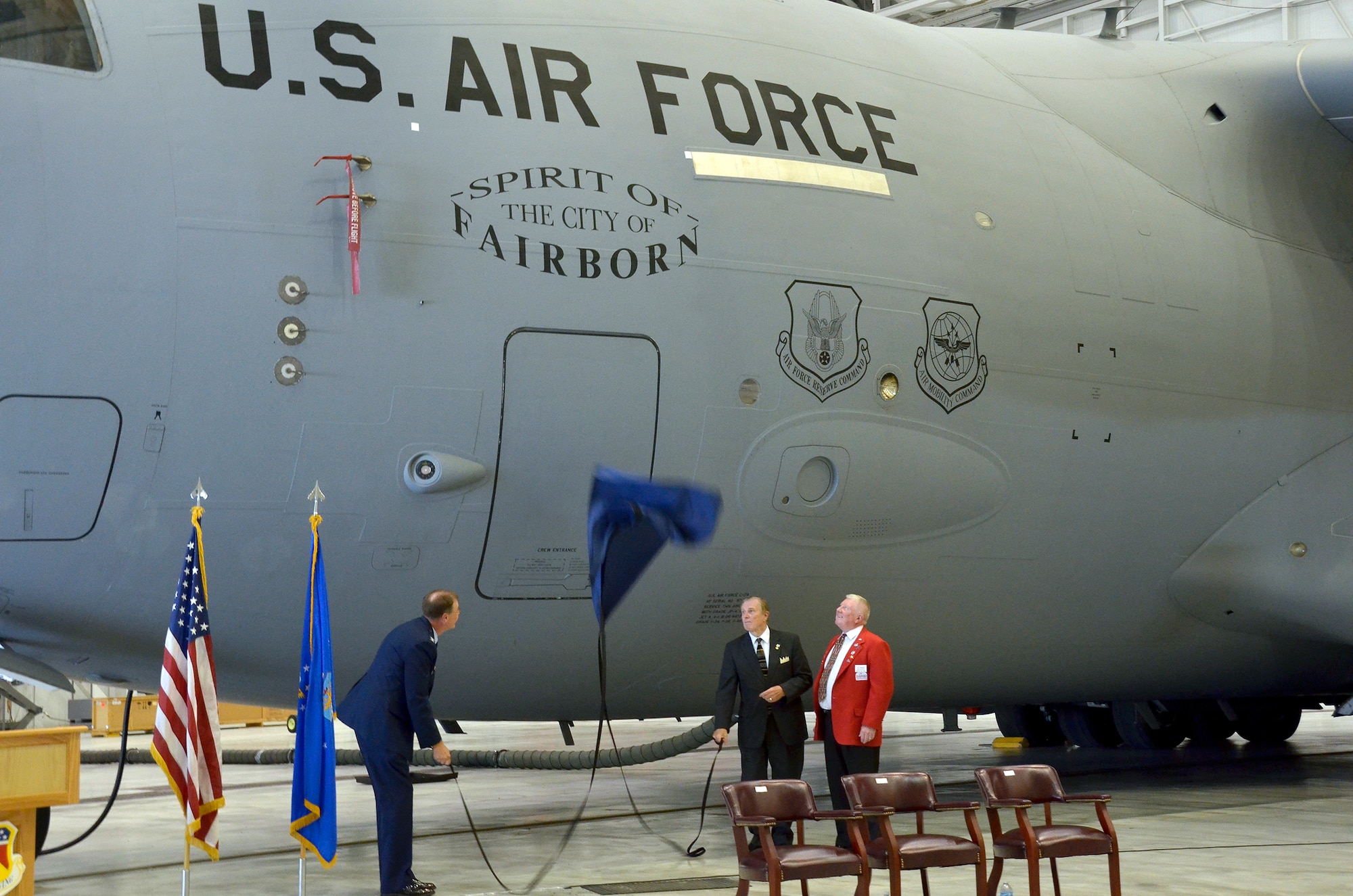 WRIGHT-PATTERSON AIR FORCE BASE, Ohio - Paul Newman, Fairborn Chamber of Commerce executive director, looks on as Col. Stephen Goeman, 445th Airlift Wing commander, and Fairborn Mayor Tom Nagel pull the curtain down together to reveal the "Spirit of the City of Fairborn" decal displayed on a 445th Airlift Wing C-17 Globemaster III during a dedication ceremony Sept. 10. More than 100 community leaders, military and civilian personnel were in attendance. (U.S. Air Force photo/Stacy Vaughn)