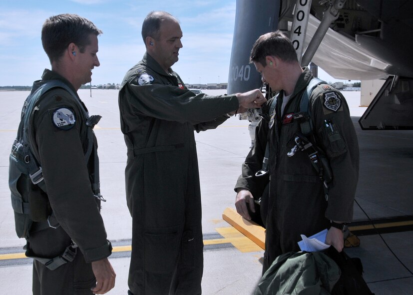 While fellow pilot Maj. Tim Rezac looks on, Maj. Ryan Bailey, 131st Operations Support Flight commander, presents Maj. Luke Jayne with his 1000 B-2 flying hour patch, Sept 14, 2013, at Whiteman AFB, Mo.  All are Guardsmen with the 131st Bomb Wing, Missouri Air National Guard.  Jayne joins an elite group of 35 B-2 pilots who have achieved 1000 or more hours in the B-2 Stealth Bomber.  (U.S. Air National Guard Photo by Senior Master Sgt. Mary-Dale Amison/RELEASED)