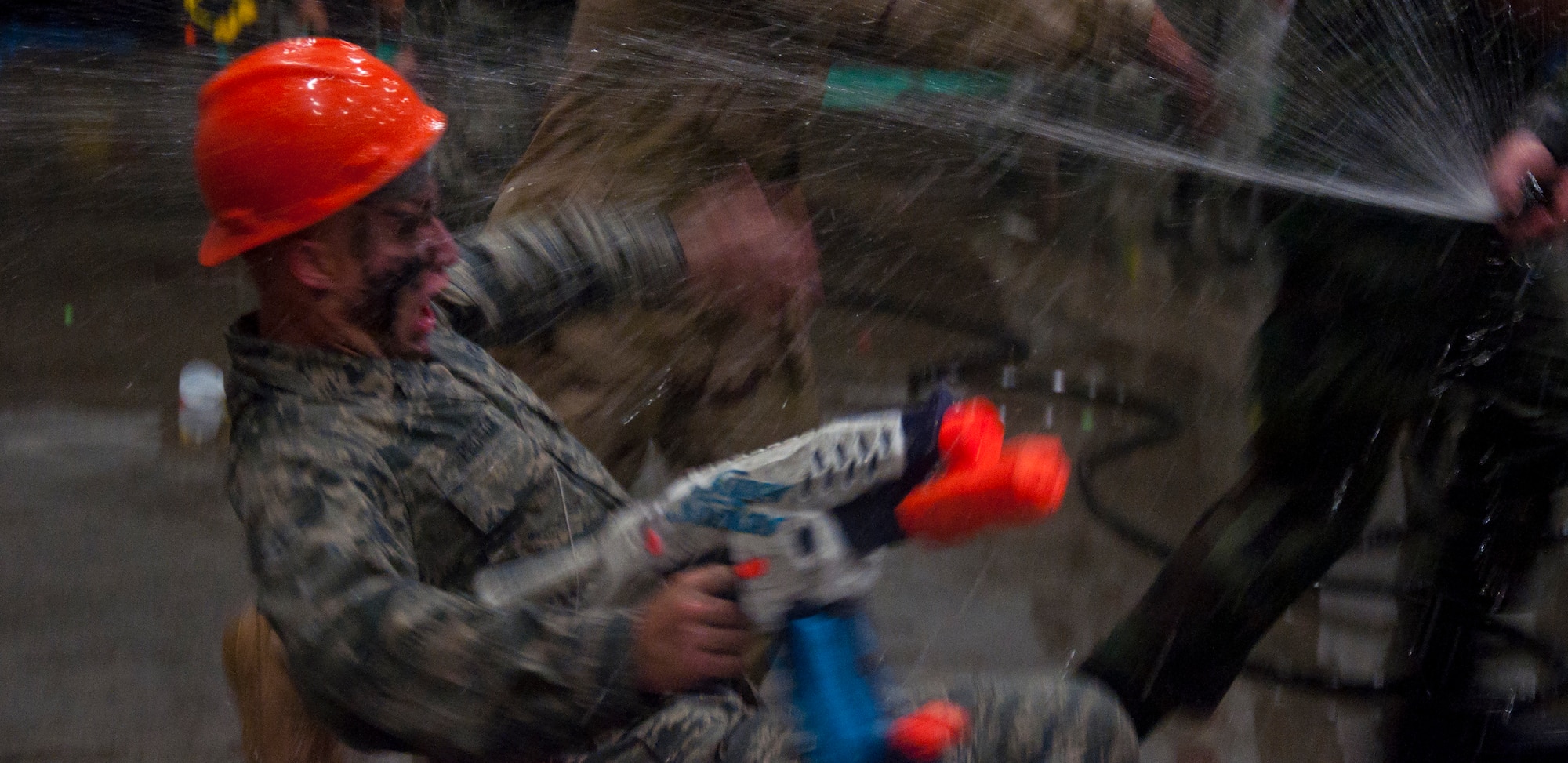 130913-F-GZ967-182 Airman 1st Class Ian Pedlow, 90th Civil Engineer Squadron, tries to avoid an incoming spray of water during an all-out water war between the various squadrons of F.E. Warren Air Force Base, Wyo. The water war was part of an enlisted combat dining-in hosted in the Peacekeeper High Bay, Bldg. 1501, Sept. 13, 2013. (U.S. Air Force photo by Airman 1st Class Brandon Valle)