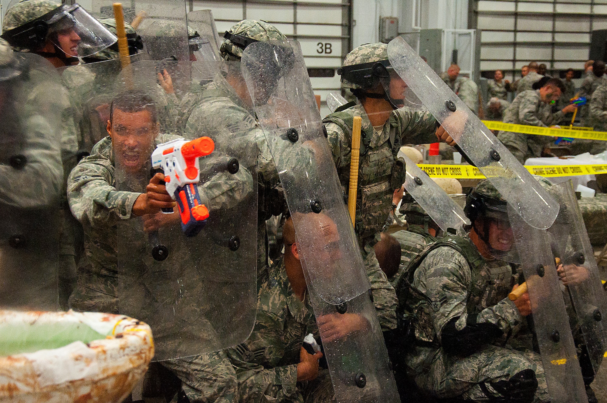 130913-F-GZ967-156 Airmen from the 90th Missile Security Forces Squadron Flight 9 use their riot gear to protect Chief Master Sgt. Michael Garrou, 90th Missile Wing command chief, during an all-out water war between the various squadrons of F.E. Warren Air Force Base, Wyo. The water war was part of an enlisted combat dining-in hosted in the Peacekeeper High Bay, Bldg. 1501, here, Sept. 13, 2013. (U.S. Air Force photo by Airman 1st Class Brandon Valle)
