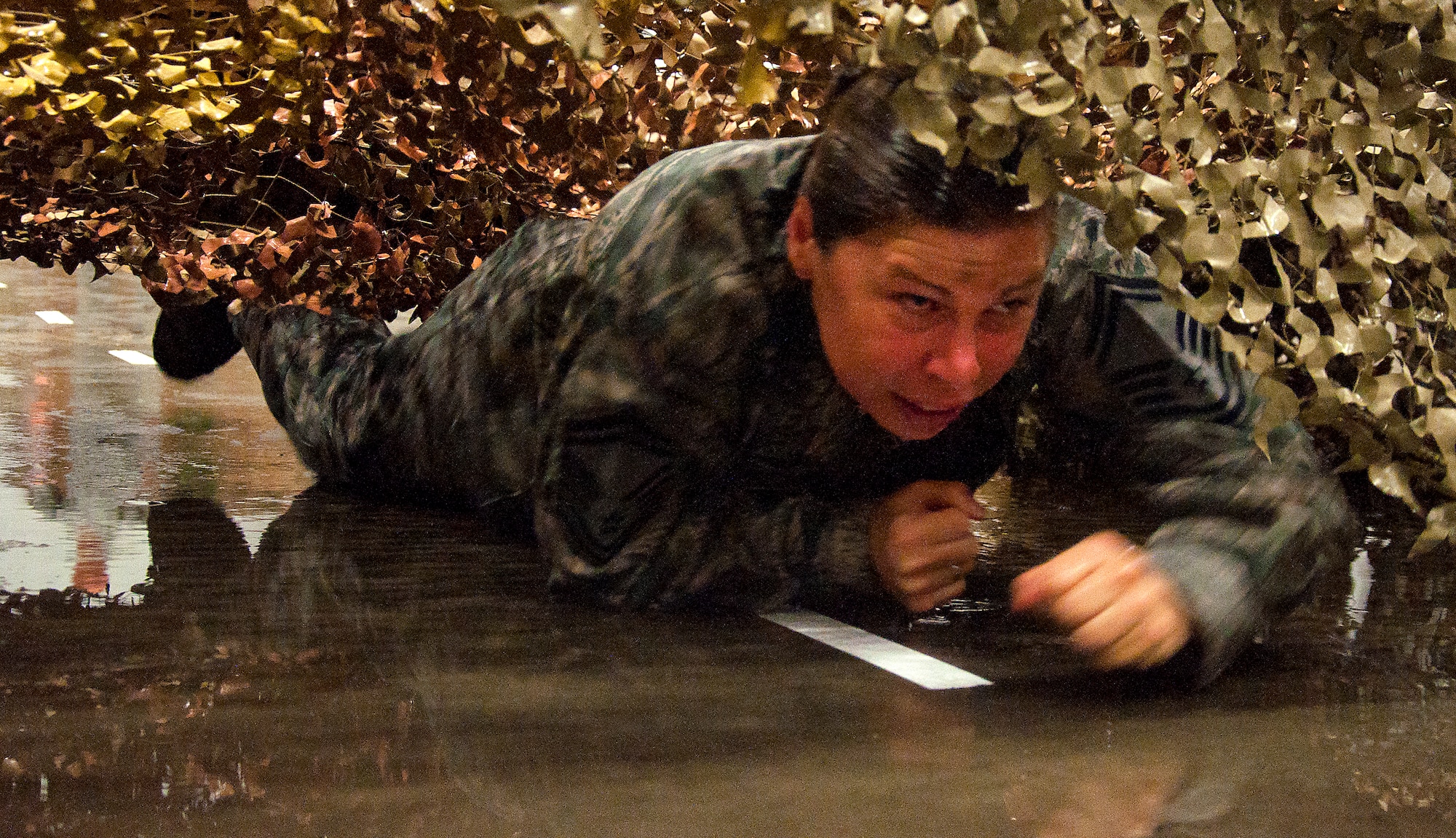 130913-F-GZ967-147 Senior Master Sgt. Jennifer Blackmarr, 90th Security Support Squadron security forces manager, performs a low crawl through a cargo net while being sprayed by water guns during the F.E. Warren Air Force Base, Wyo., enlisted combat dining-in Sept. 13, 2013. The cargo net was part of an obstacle course designed as a punishment for anyone who broke a “Rule of the Mess” during the dining-in. (U.S. Air Force photo by Airman 1st Class Brandon Valle)
