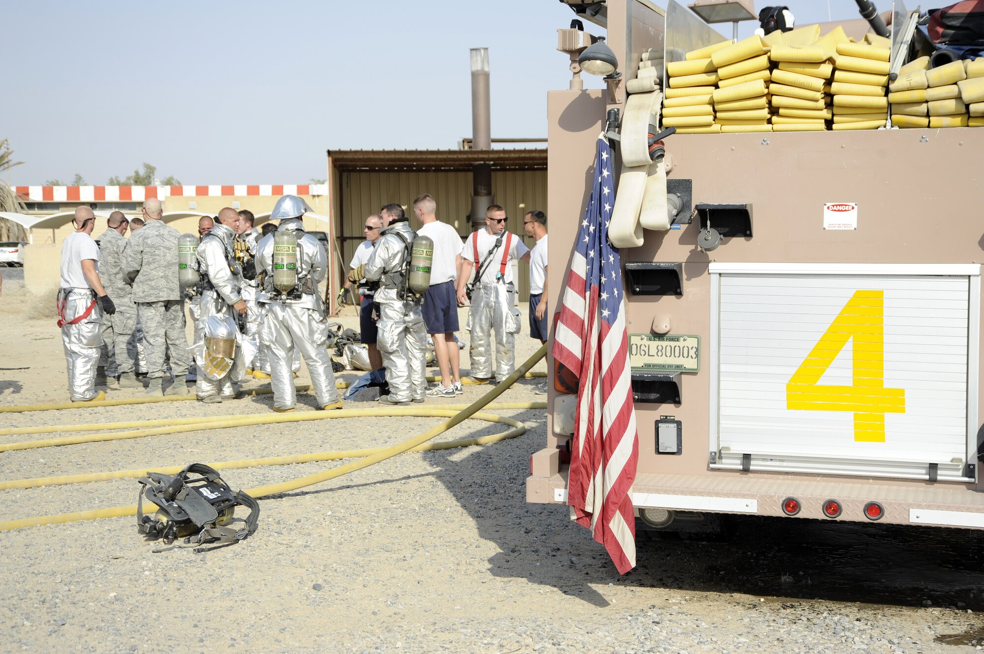Members of the 386th Air Expeditionary Wing group together to discuss what took place in the shipping container here, Sept. 16, 2013.  The 386th Expeditionary Civil Engineer squadron fire department conducted a live fire exercise and invited wing leadership to partake in it. A live fire is an uncontrolled fire in a controlled environment. This exercise was conducted to get the firefighters additional training while deployed here.  (U.S. Air Force photo by Master Sgt. Christopher A. Campbell)