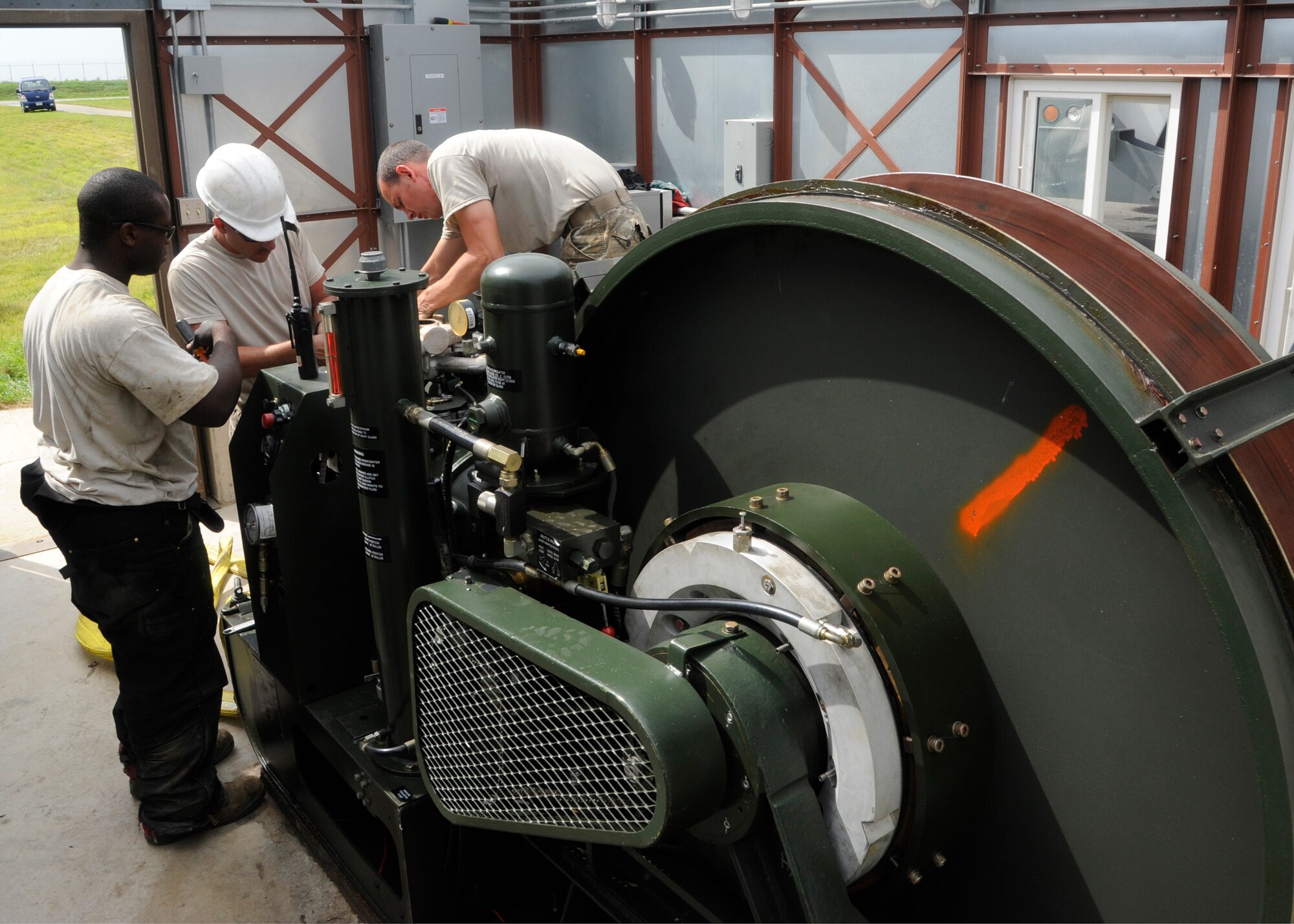Staff Sgt. Jerrell Washington, Master Sgt. Jeffrey Jones and Tech. Sgt. Jeffrey Zahniser, 8th Civil Engineer Squadron, install the intake and exhaust manifold on the rewind engine used for the new Barrier Arresting Kit-12 systems on the flight line at Kunsan Air Base, Republic of Korea, Sept. 2, 2013. The Kunsan flight line is equipped with three barriers, each capable of stopping an aircraft should an in-flight emergency take place. (U.S. Air Force photo by Staff Sgt. Jessica Haas/Released)