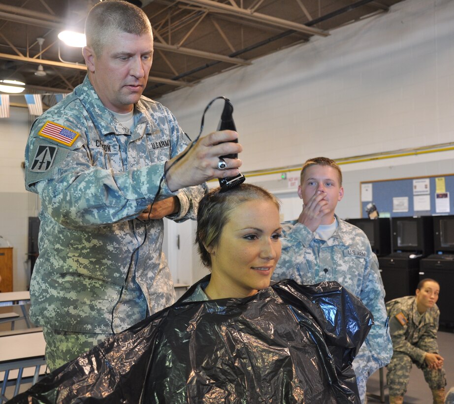 Army Sgt 1st Class. Bernie Crafton begins clipping off Army Staff Sgt. Erin Emminger’s hair at the Shelbyville Ind., National Guard Armory, Sept. 14, 2013. Emminger raised more than $1,000 for a fellow Indiana National Guard soldier Spc. Jeremiah Morgan, who is battling cancer. Emminger’s commander authorized an exception to policy to allow the departure from normal standards. U.S. Army photo by Sgt. Dana Brewer