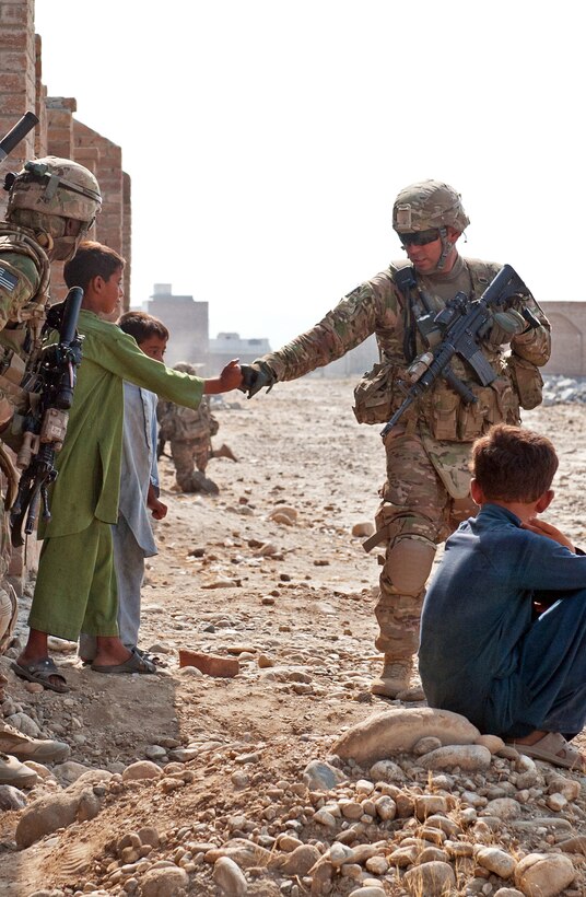 U.S. Army Staff Sgt. Drake Rivas bumps fists with an Afghan boy during a reconnaissance mission in a village south of Forward Operating Base Fenty in Afghanistan's Nangarhar province, Sept. 8, 2013. Rivas is assigned to the 1st Cavalry Division's 4th Squadron, 9th Cavalry Regiment, 2nd Armored Brigade Combat Team.