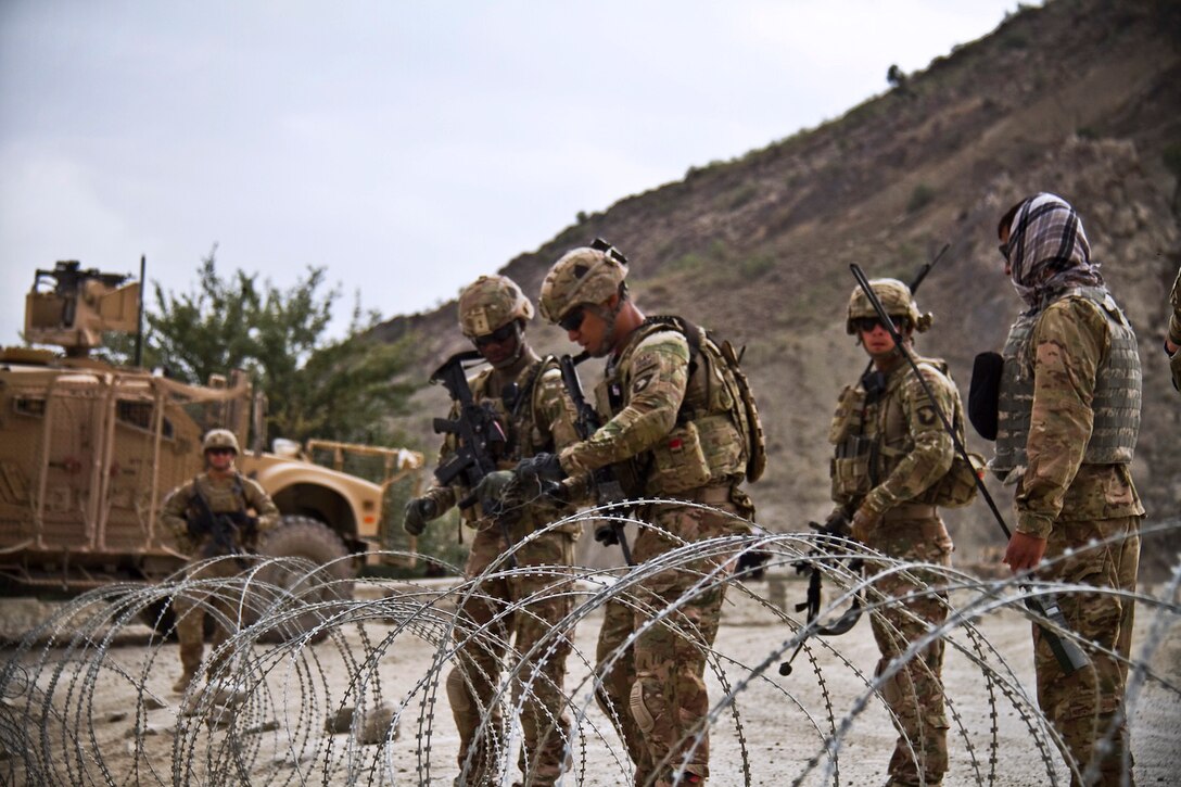 U.S. soldiers use concertina wire to set up a road block while on a security mission in Paktya province, Afghanistan, Aug. 31, 2013.