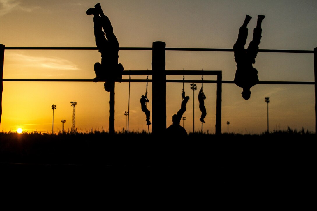 Marines flip over obstacles and climb ropes as the sun peers over the horizon.  The training was part of an obstacle course during which Marines retained team and morale building techniques. More than 90 Marines and sailors, made up of different military occupational specialties, went through months of various training exercises and courses to ensure the success of Africa Partnership Station 13.