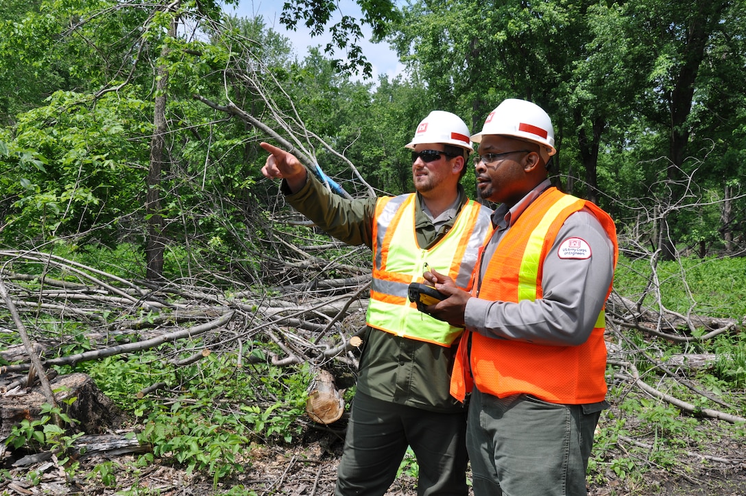 Dan Reburn, left, operations, and Bobby Jackson, operations, discuss a reforestation project during a tree planting on a Mississippi River island near Red Wing, Minn., June 10.