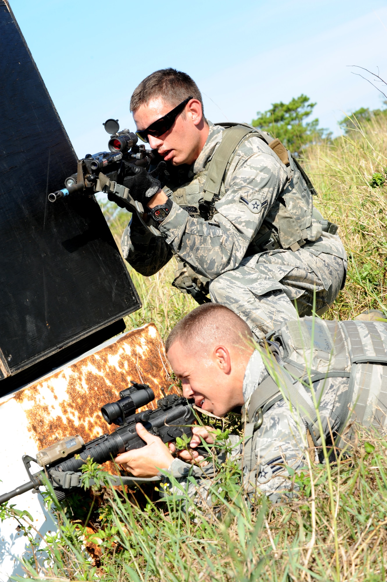 U.S. Air Force Senior Airman Brandon Spears and Airman Jeffrey Schmidt, 18th Security Forces Squadron force response members, take cover behind a barrier during a training course on Kadena Air Base, Japan, Sept. 6, 2013. 18th SFS personnel participated in a Shoot, Move, Communicate training course, which provides security forces with a realistic simulation of actually being on a battlefield and puts personnel through squad and team formations and movements while encountering an opposing force. (U.S. Air Force photo by Airman 1st Class Hailey R. Davis)