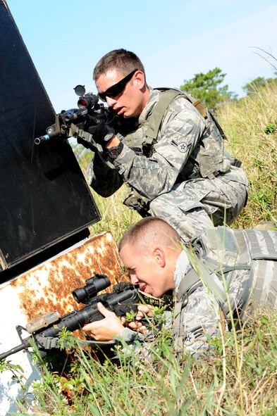 U.S. Air Force Senior Airman Brandon Spears and Airman Jeffrey Schmidt, 18th Security Forces Squadron force response members, take cover behind a barrier during a training course on Kadena Air Base, Japan, Sept. 6, 2013. 18th SFS personnel participated in a Shoot, Move, Communicate training course, which provides security forces with a realistic simulation of actually being on a battlefield and puts personnel through squad and team formations and movements while encountering an opposing force. (U.S. Air Force photo by Airman 1st Class Hailey R. Davis)