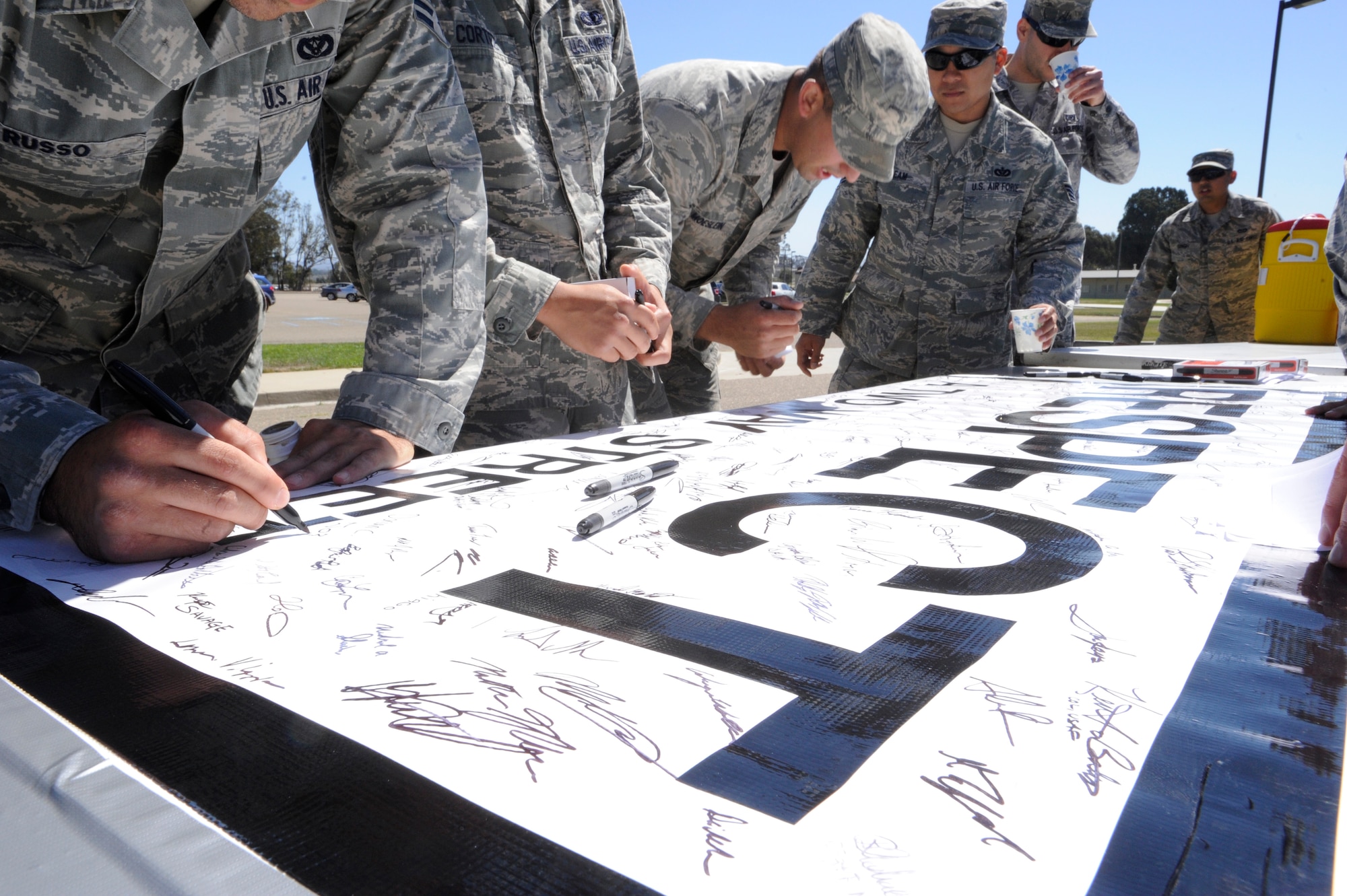 VANDENBERG AIR FORCE BASE, Calif. -- Members of a 30th Civil Engineer Squadron team sign a banner signifying their commitment to respecting others during the "Get R.E.A.L. Walk" here Tuesday, Sept. 17. During the walk, which was hosted by the 381st Training Group, Team V members were asked to change the culture and pledge their commitment to preventing sexual assaults by signing banners representing Respect, Equality, Accountability and Leadership. (U.S. Air Force photo/Airman Yvonne Morales)